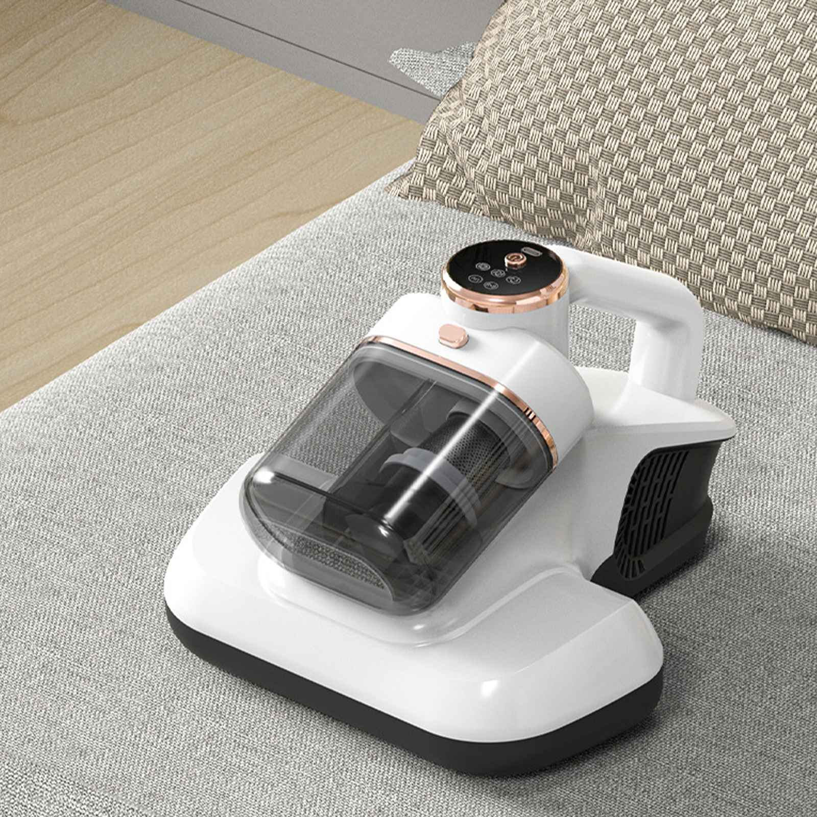 Weißer kabelloser Staubsauger mit transparentem Staubbehälter liegt auf einem grauen Sofa neben einem gemusterten beigen Kissen.
