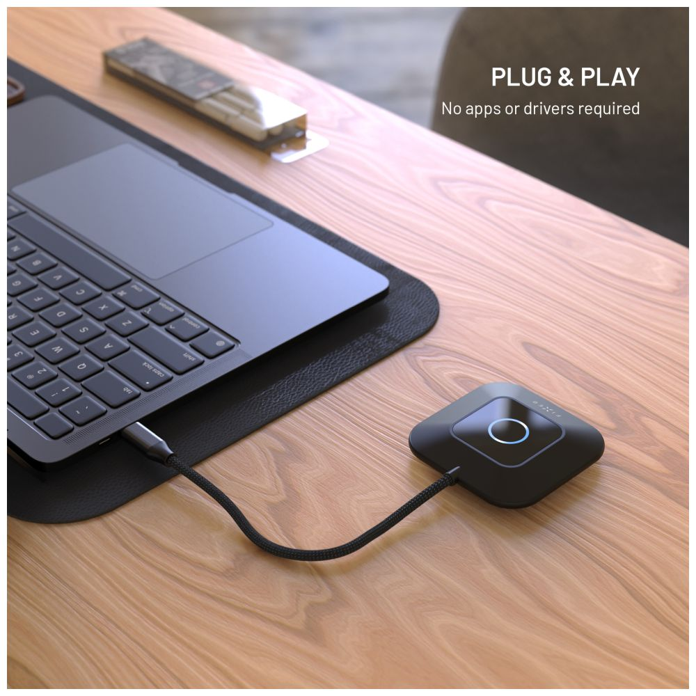 Laptop ist über ein Kabel mit einem schwarzen quadratischen Gerät auf einem Holztisch verbunden. Ein Stifthalter ist sichtbar.