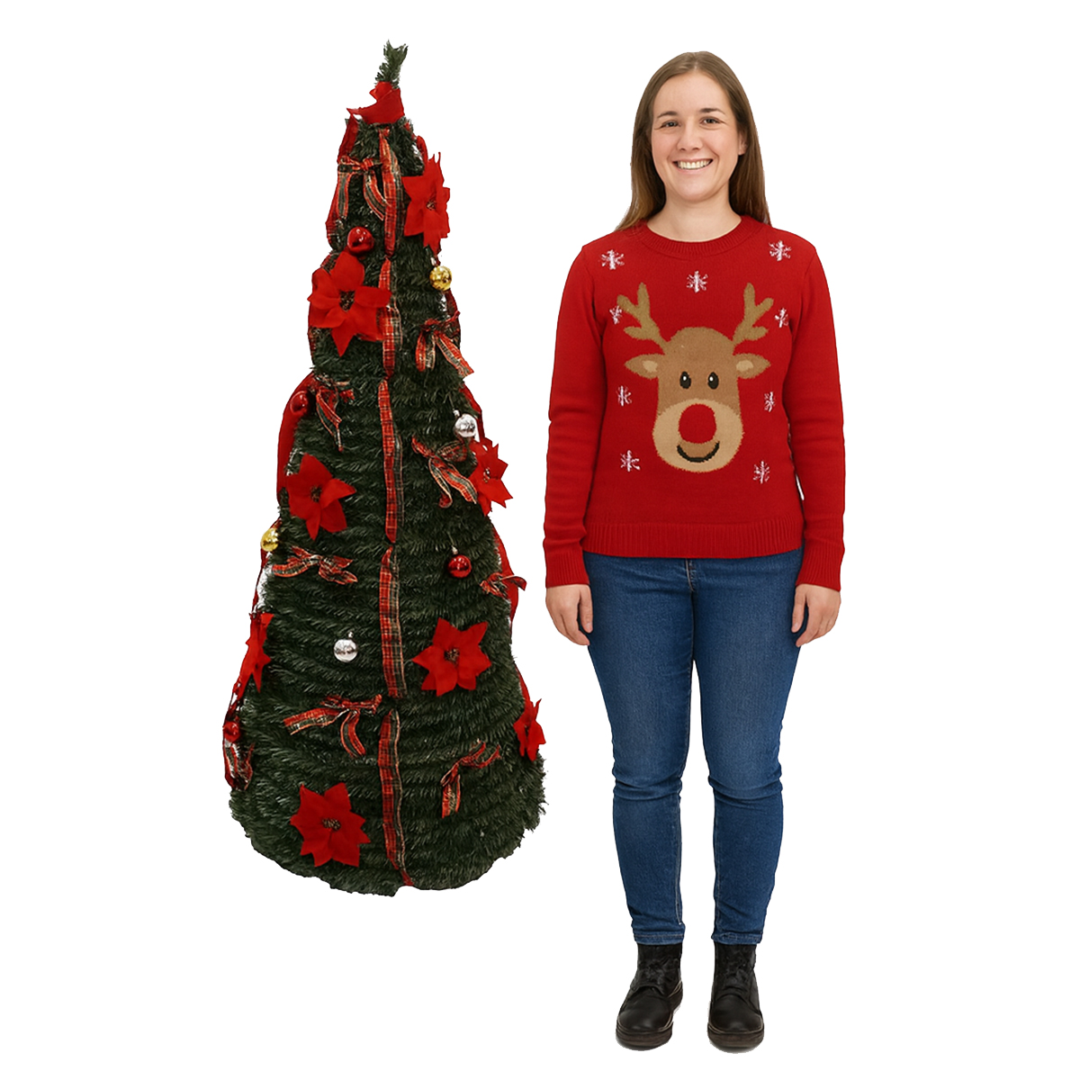 Una mujer con un suéter de reno está junto a un árbol de Navidad decorado. El árbol tiene cintas y adornos rojos.