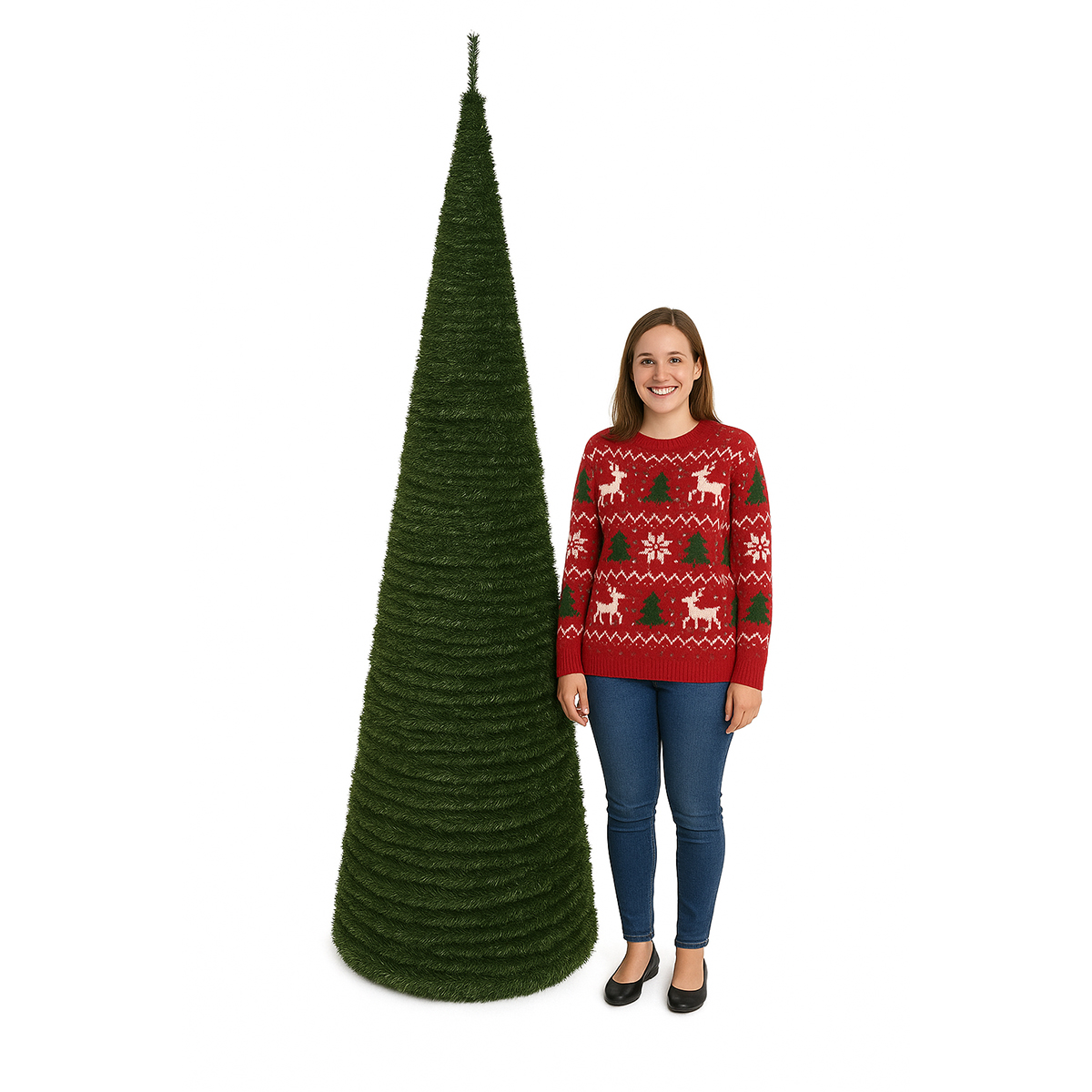 Una mujer está junto a un árbol de Navidad verde y cónico, con un suéter rojo con diseños festivos, jeans azules y zapatos negros.