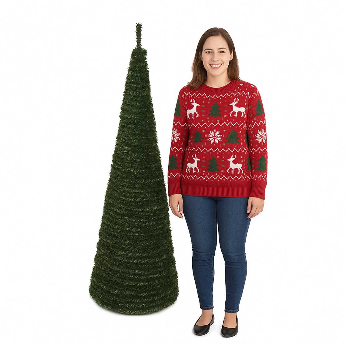 Una mujer con un suéter navideño rojo y jeans está junto a un árbol de Navidad verde sobre un fondo blanco.