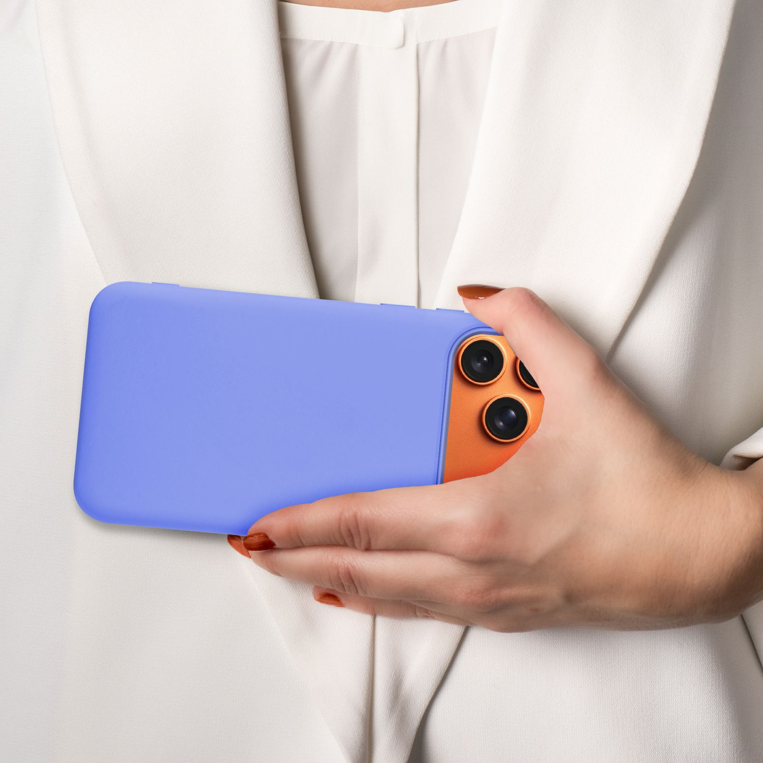 Eine Person hält ein Telefon in einer blauen Hülle. Das Telefon hat eine orangefarbene Rückseite und mehrere Linsen. Die Person trägt einen weißen Blazer.