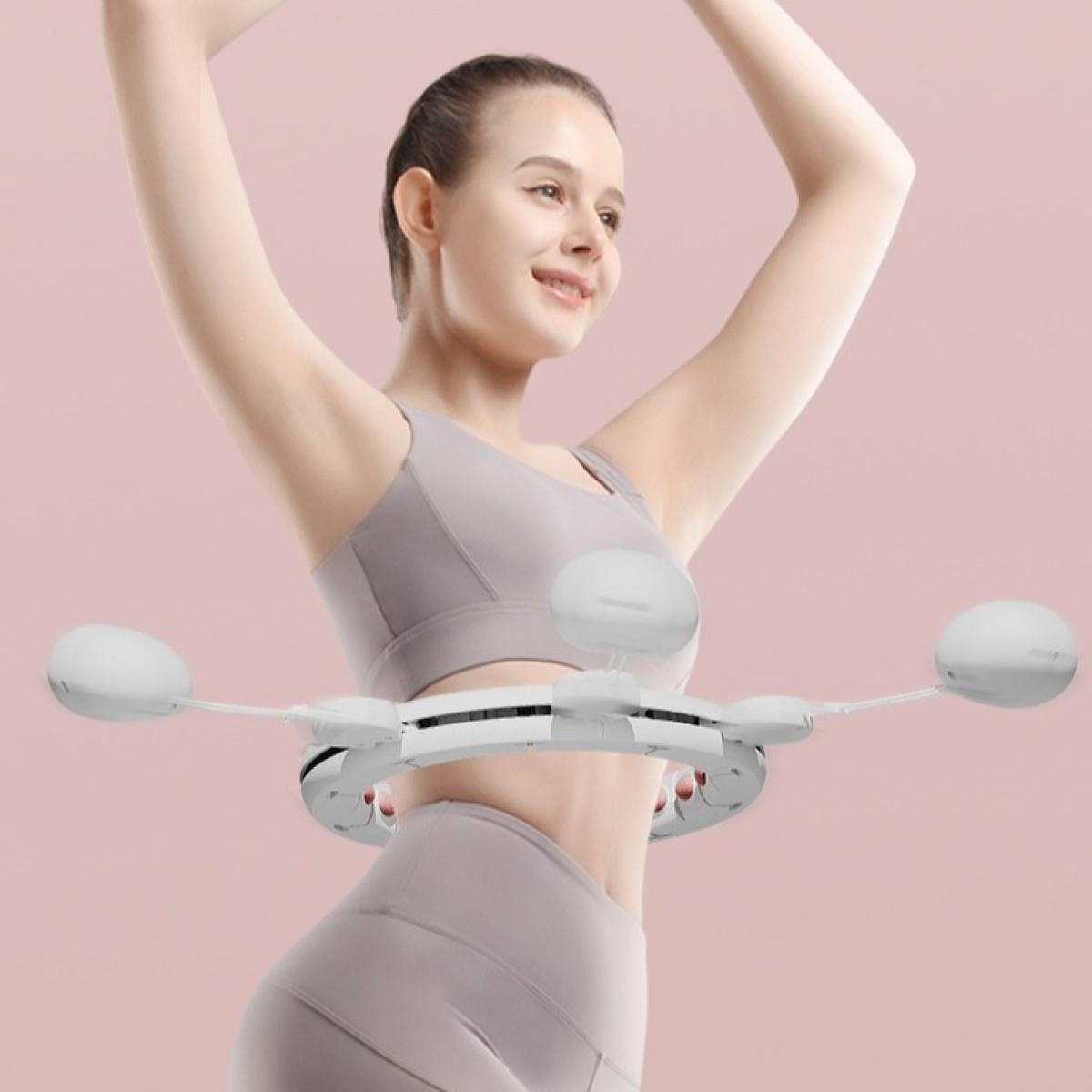 Frau in grauer Sportkleidung, die einen weißen, gewichteten Hula-Hoop-Reifen benutzt. Sie lächelt mit erhobenen Armen. Rosa Hintergrund.