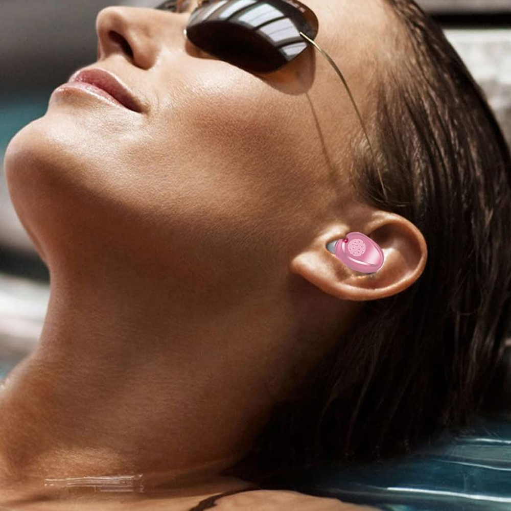 Eine Frau mit Sonnenbrille und einem rosa Ohrhörer. Sie ist im Wasser, ihr Gesicht und ihre Schulter sind sichtbar. Der Hintergrund ist verschwommen.