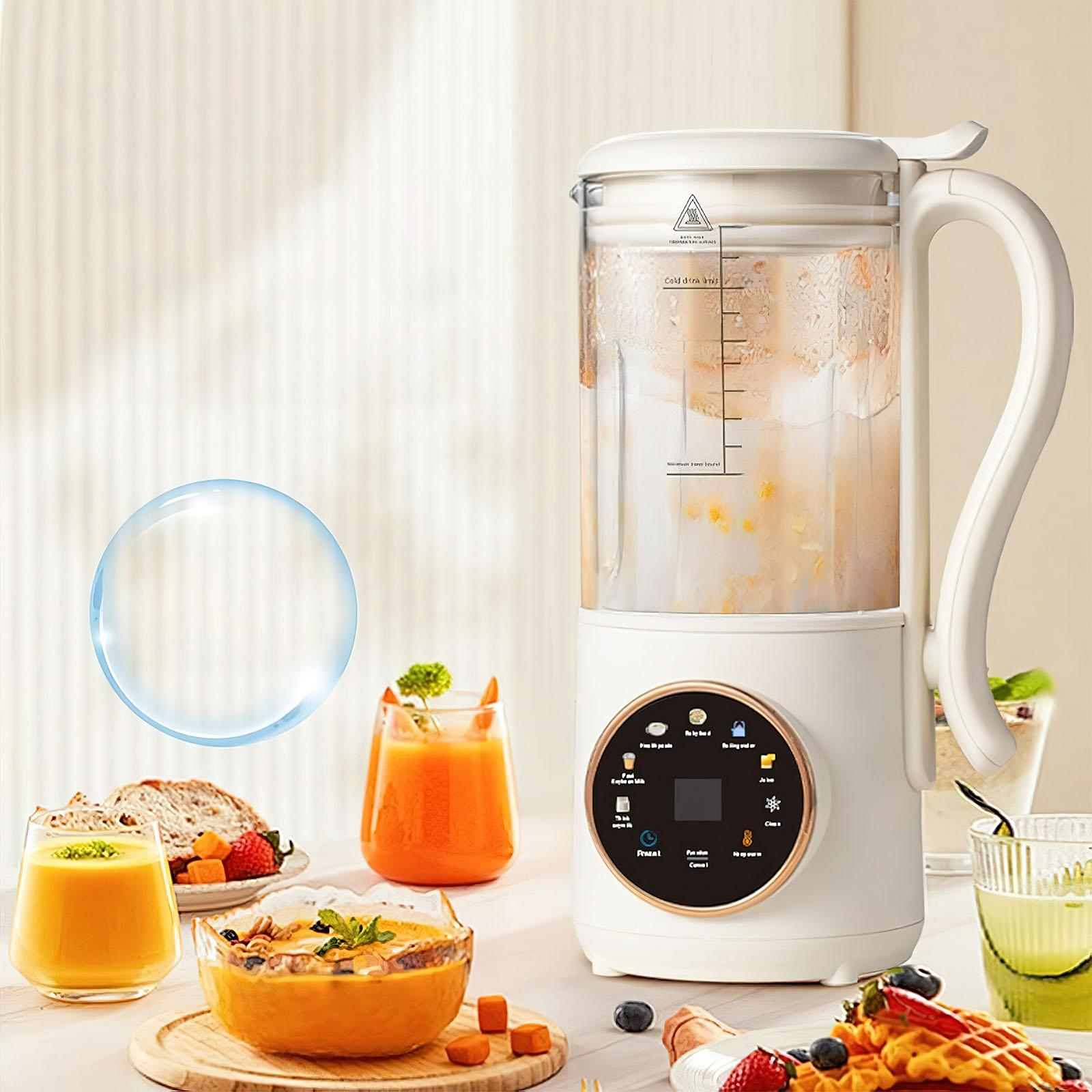 Ein weißer Mixer mit Griff, umgeben von Orangensaft, Suppe und Obst, auf einem Tisch.
