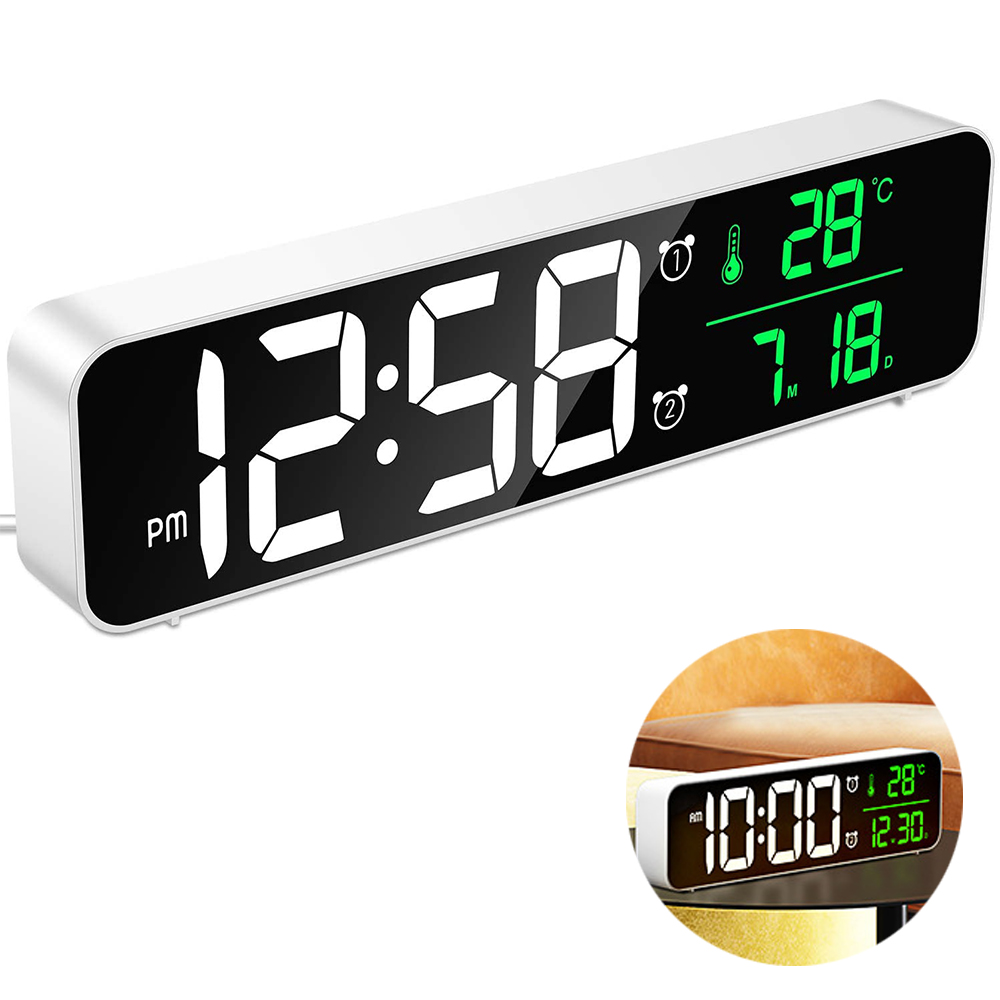 Ein digitaler Wecker zeigt 12:58 PM, 28°C und 7.18 an. Er ist weiß mit schwarzem Display und einem kleinen inset Bild.