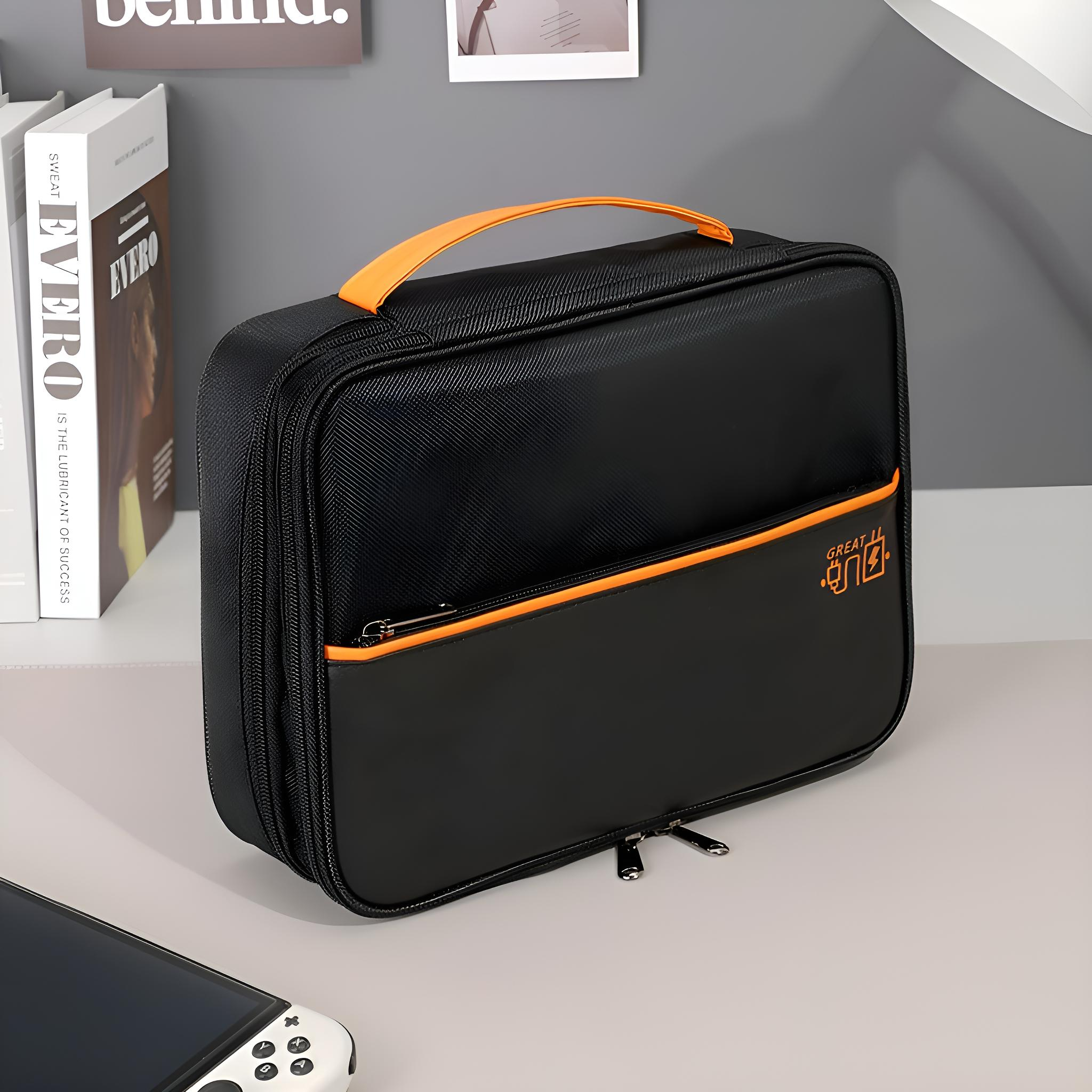Schwarze Tasche mit orangefarbenem Griff und Akzenten. Enthält einen Reißverschluss und den Text 'GREAT ONE'. Bücher sind im Hintergrund.
