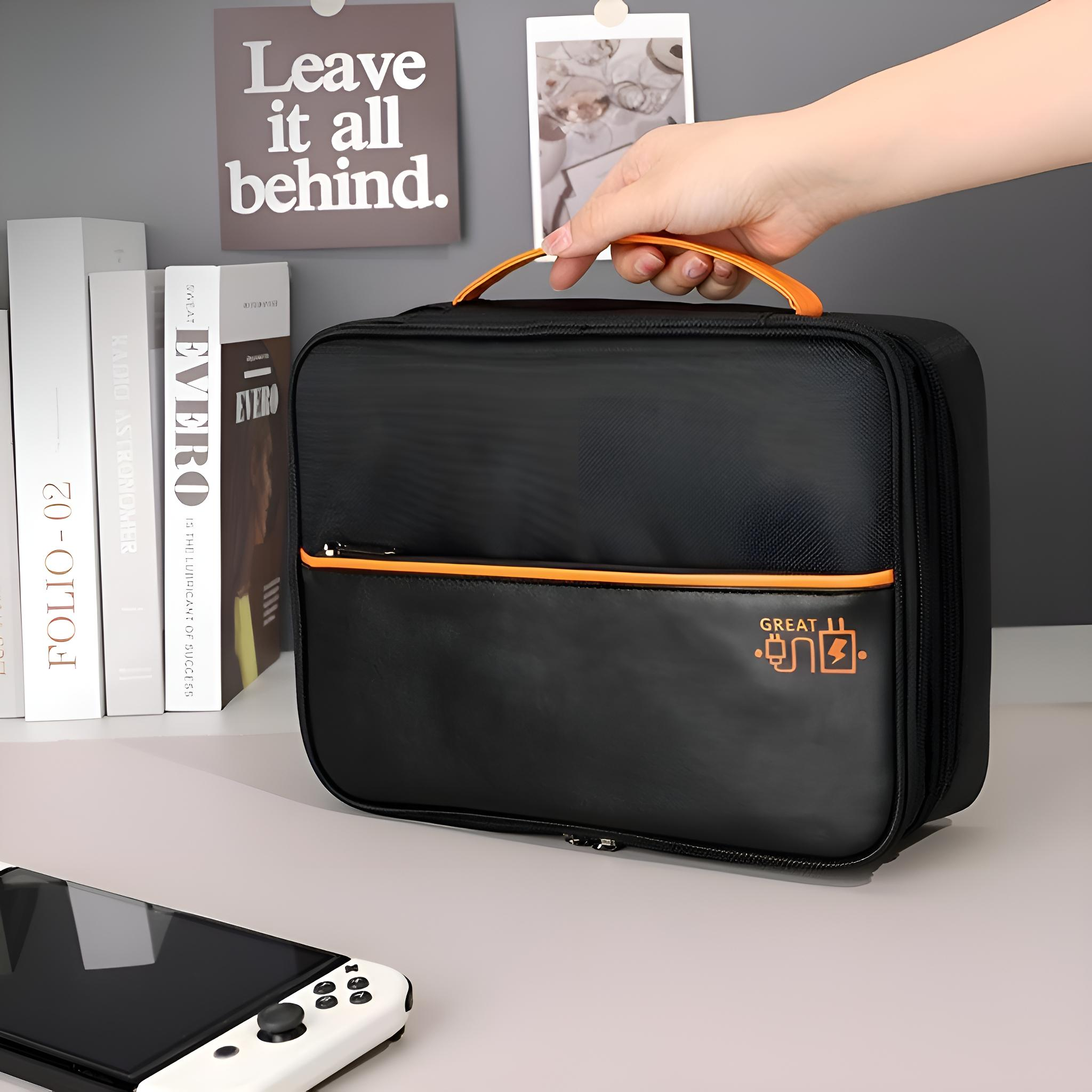 Eine Person hält eine schwarze Tasche mit orangen Akzenten. Bücher und eine Spielkonsole sind im Hintergrund.