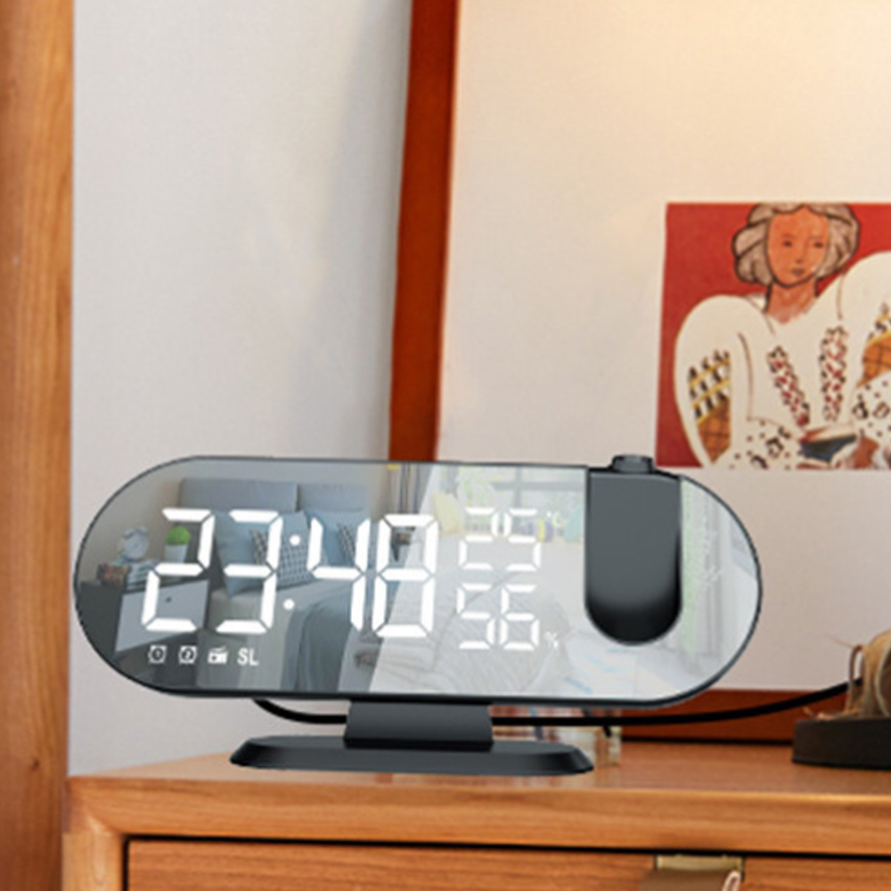Eine schwarze Digitaluhr zeigt 23:48 an. Die Spiegeloberfläche spiegelt einen Raum wider. Die Uhr steht auf einem Nachttisch aus Holz.