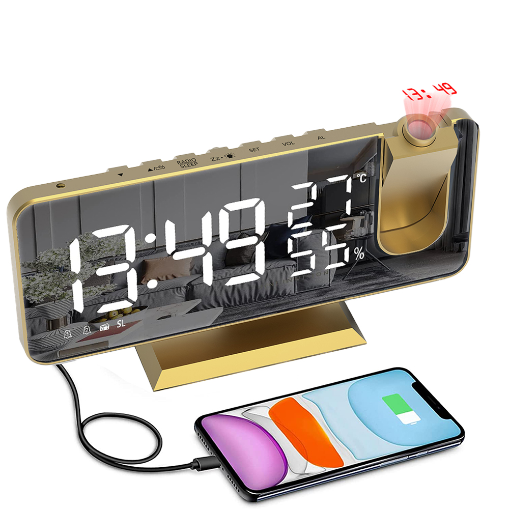 Eine goldene Digitaluhr zeigt Zeit und Temperatur an. Ein Telefon wird über ein Kabel aufgeladen. Die Zeit wird an die Wand projiziert.