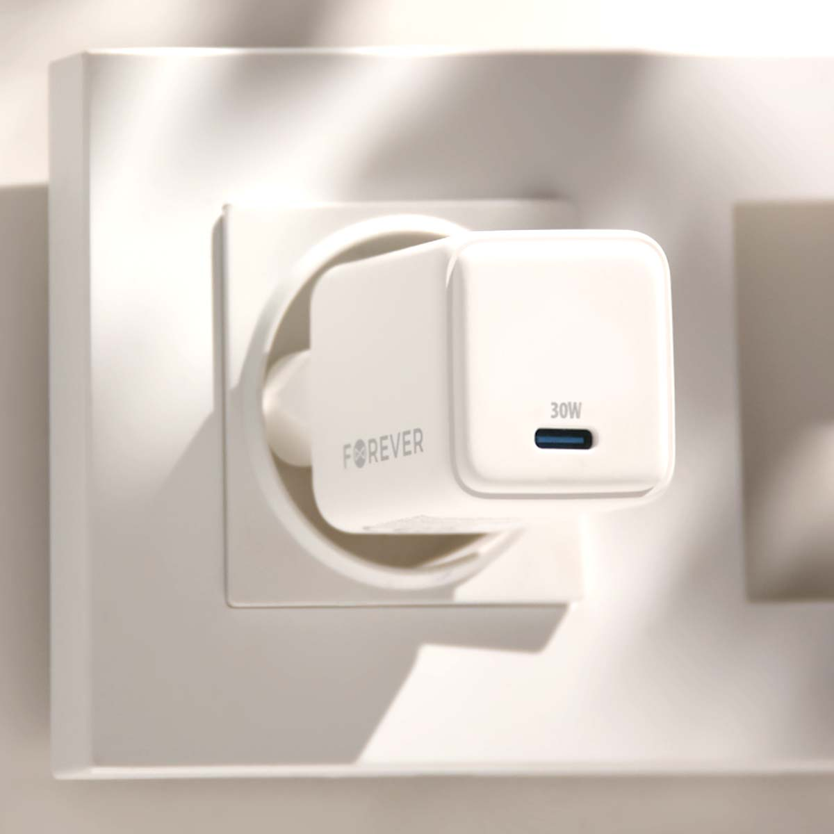 Un caricabatterie Forever bianco è collegato a una presa a muro. Il caricabatterie ha una porta USB blu ed è etichettato '30W'.