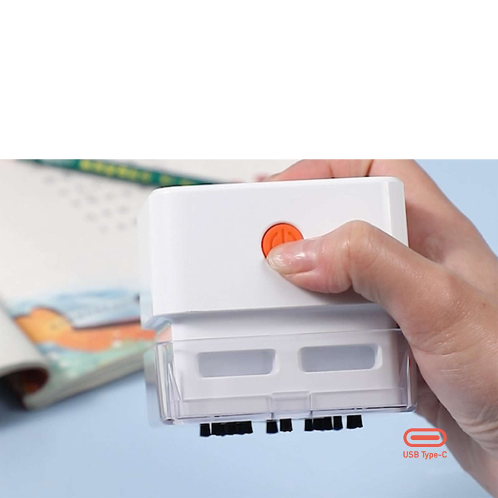 Eine Hand drückt einen orangefarbenen Knopf auf einem weißen Gerät über einem Notizbuch mit USB Type-C-Etikett.
