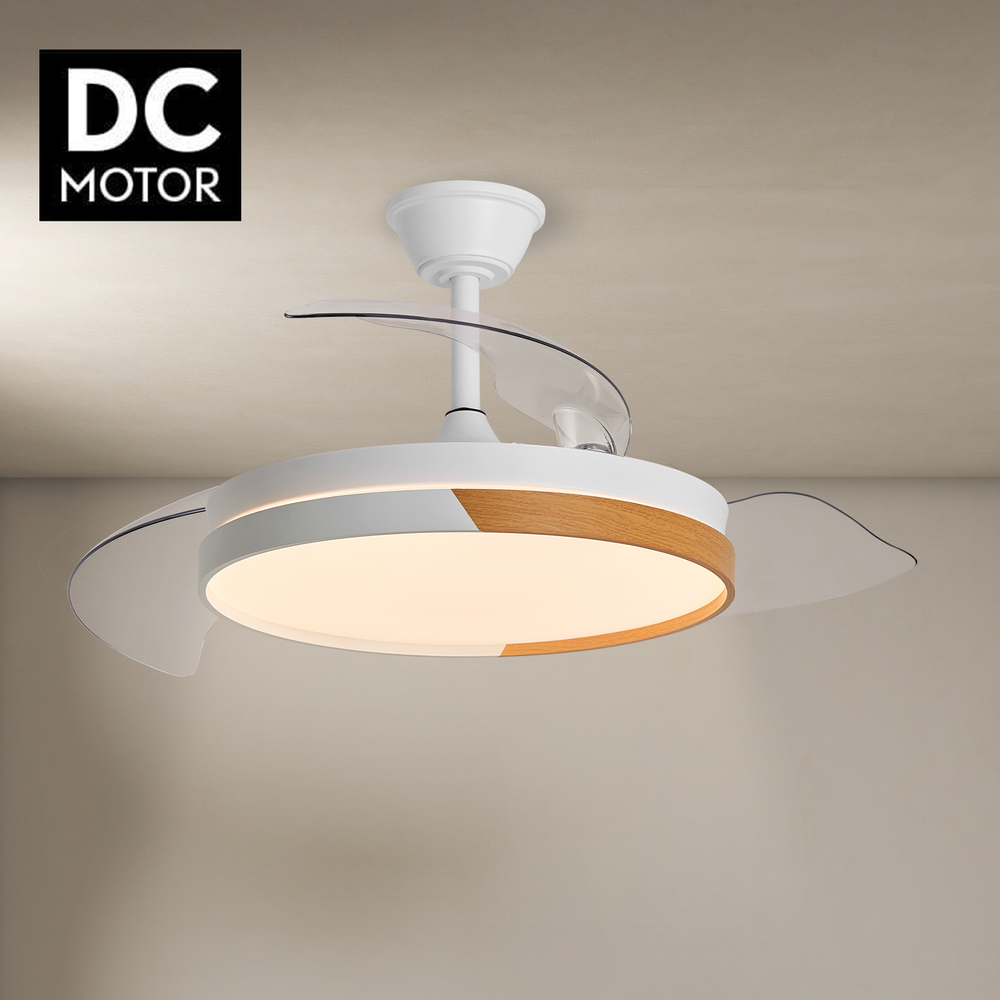 Ventilador de techo blanco con aspas transparentes y luz. El ventilador tiene un acabado en madera y blanco. Texto 'DC MOTOR' arriba a la izquierda.