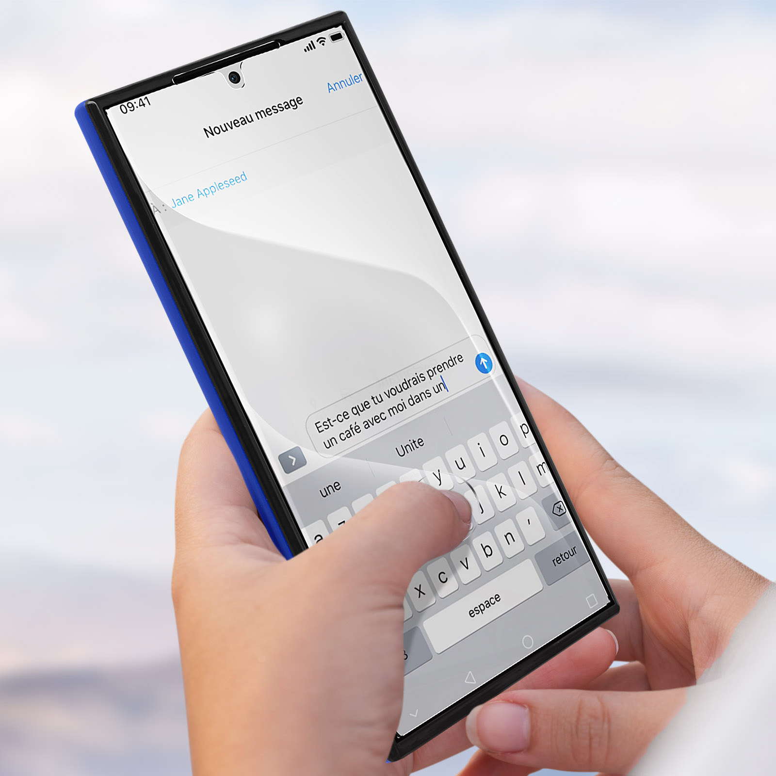 Mano che tiene uno smartphone con un messaggio di testo in francese. Digitazione sulla tastiera. Telefono blu e nero.