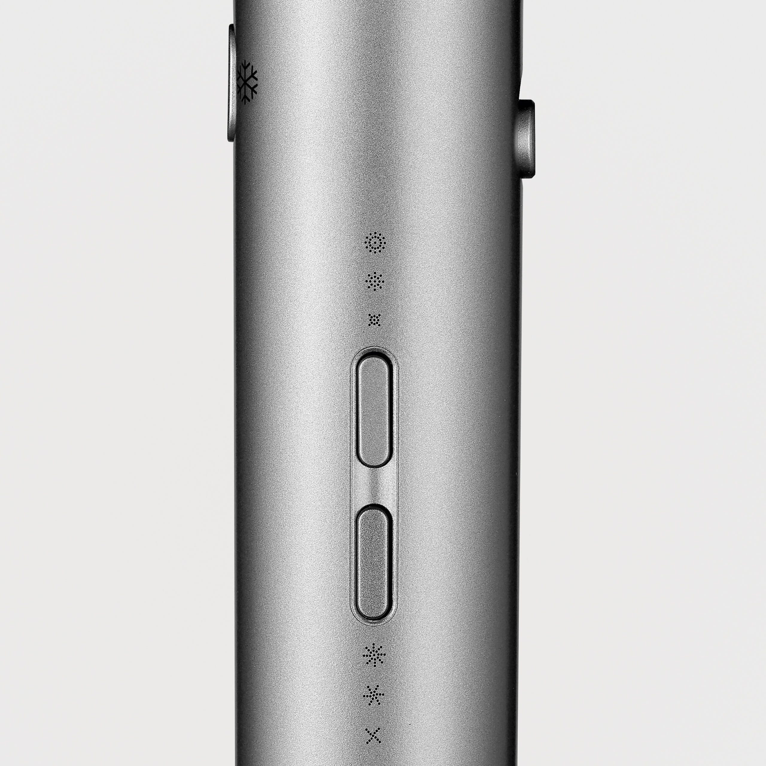 Zbliżenie metalowej suszarki do włosów. Ma przyciski i symbole, takie jak płatek śniegu i wentylator. Tło jest białe.