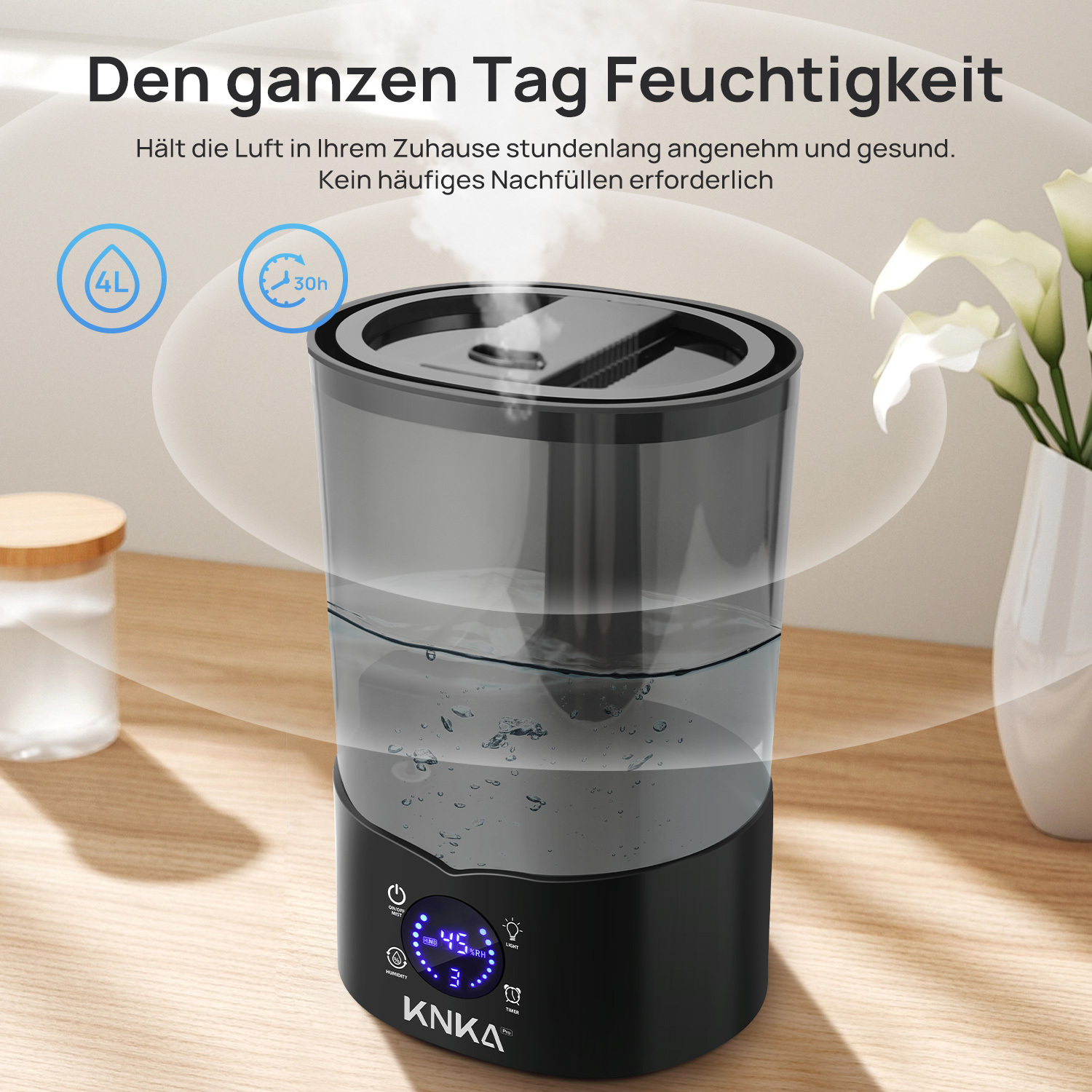 Ein schwarz-grauer Luftbefeuchter mit Digitalanzeige, eine weiße Vase mit Blumen und ein kleines Glas auf einer Holzoberfläche.