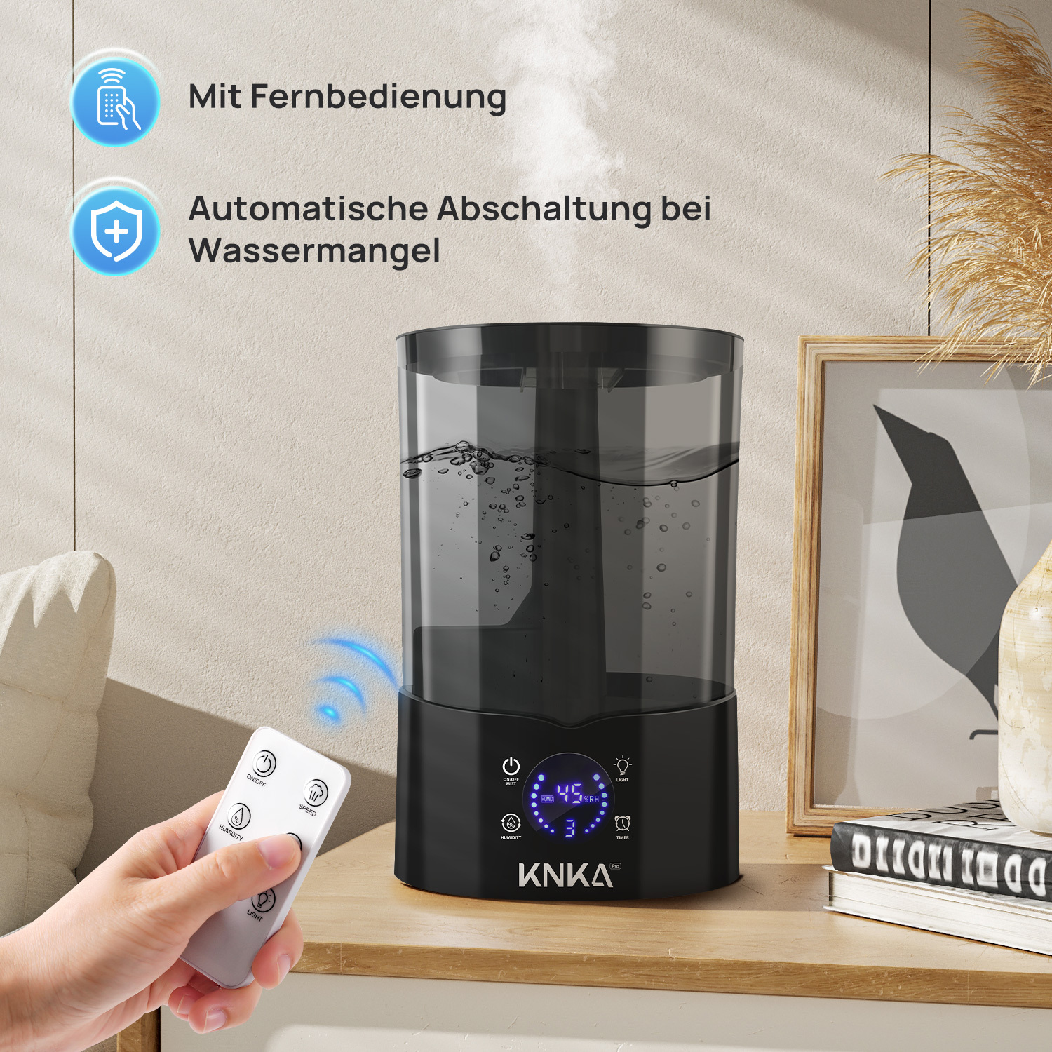 Ein schwarzer Luftbefeuchter mit Fernbedienung steht auf einem Holztisch. Wasserdampf steigt auf. Eine Hand hält die Fernbedienung.