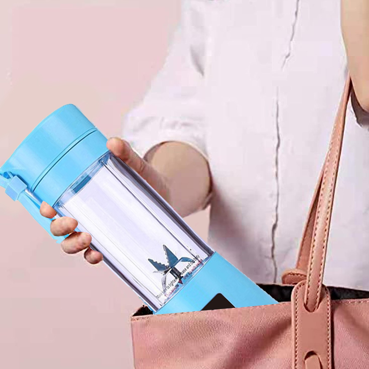 Eine Person hält einen blauen und transparenten tragbaren Mixer und legt ihn in eine rosa Tasche. Die Person trägt ein weißes Hemd.