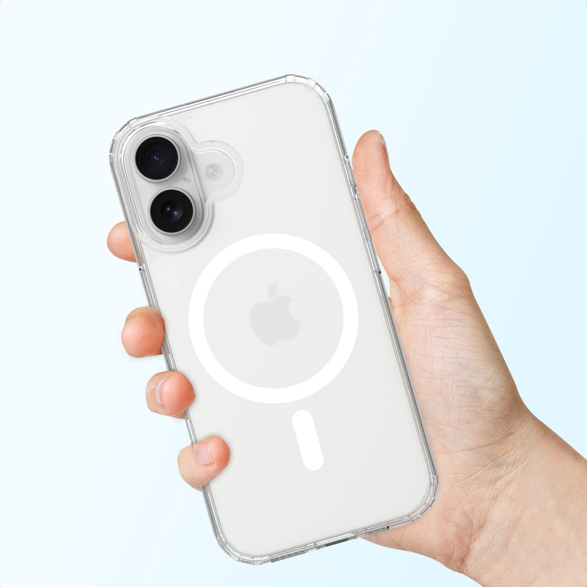 Une main tenant une coque de téléphone transparente avec un iPhone à l'intérieur. Le téléphone a un logo Apple blanc et un cercle magnétique. Fond bleu clair.