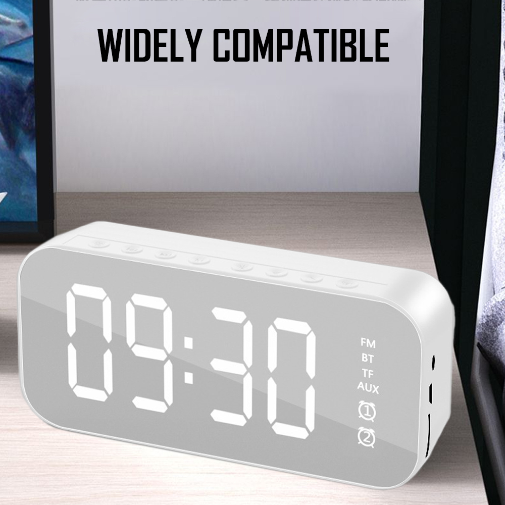 Eine weiße Digitaluhr zeigt 09:30 Uhr an. Sie hat Knöpfe und Anschlüsse. Der Hintergrund zeigt eine Holzoberfläche und den Text 'WIDELY COMPATIBLE'.