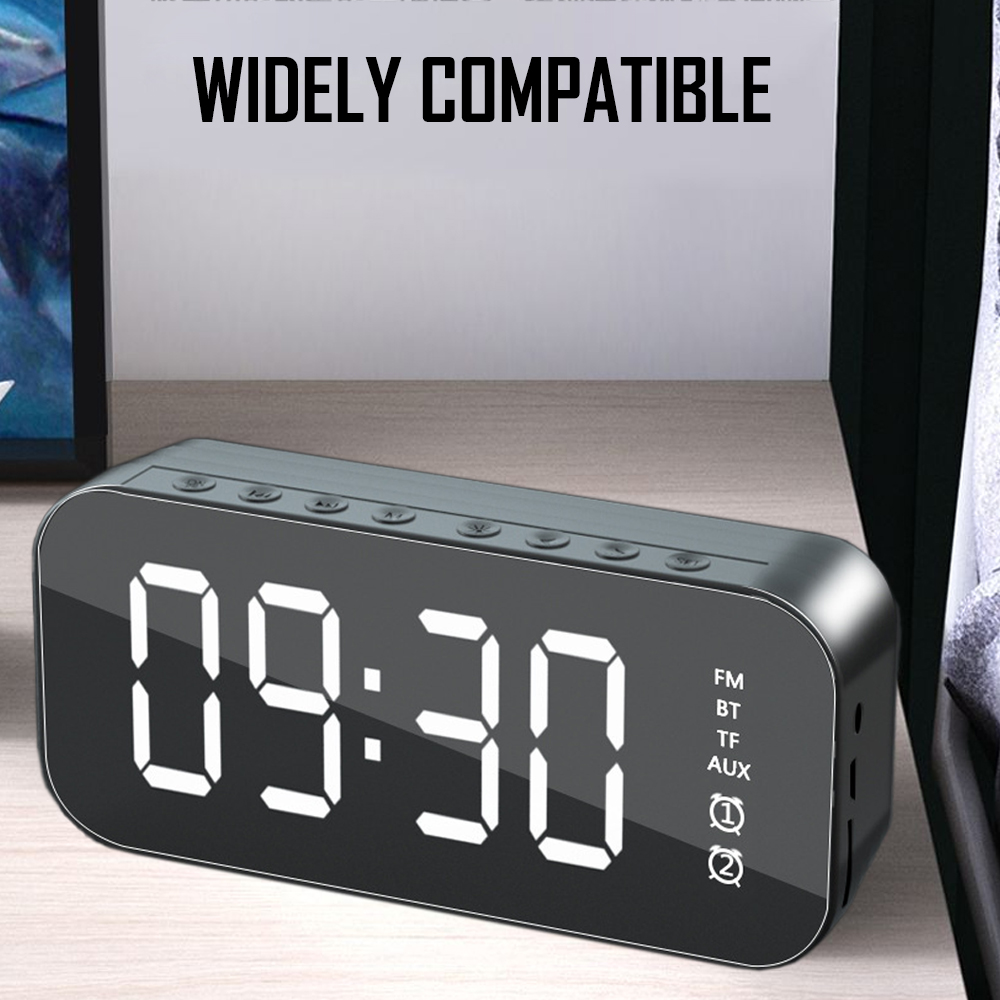 Eine Digitaluhr zeigt 09:30 an. Die Uhr ist schwarz mit weißen Zahlen und Beschriftungen. Sie steht auf einer Holzoberfläche mit weißem Hintergrund.