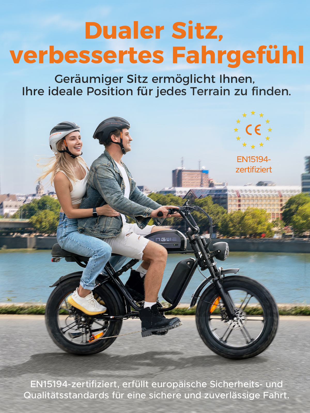 Ein Paar fährt mit einem Elektrofahrrad. Das Fahrrad ist schwarz, und sie tragen Helme. Im Hintergrund sind ein Fluss und Gebäude zu sehen.