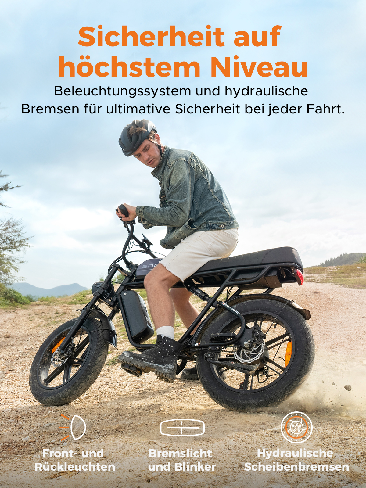 Ein Mann auf einem schwarzen E-Bike mit Helm. Das Fahrrad hat Front- und Rücklichter, Bremslichter und hydraulische Scheibenbremsen. Der Hintergrund ist eine unbefestigte Straße.
