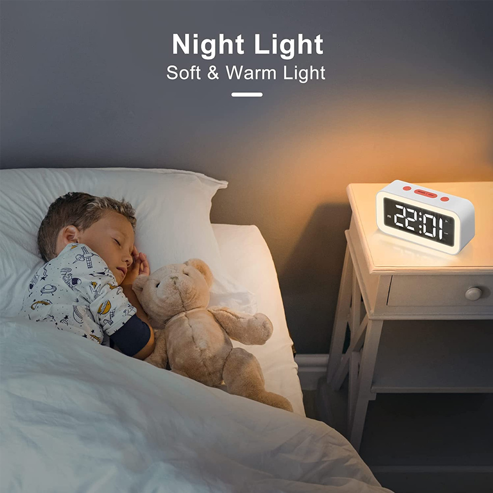 Ein schlafender Junge mit einem Teddybär im Bett neben einem Nachttisch mit einer leuchtenden Uhr. Die Zeit ist 22:01.