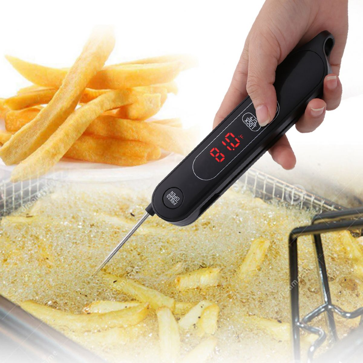 Eine Hand hält ein schwarzes Thermometer, das die Öltemperatur mit Pommes misst. Pommes sind im Öl und auf einem Teller im Hintergrund.