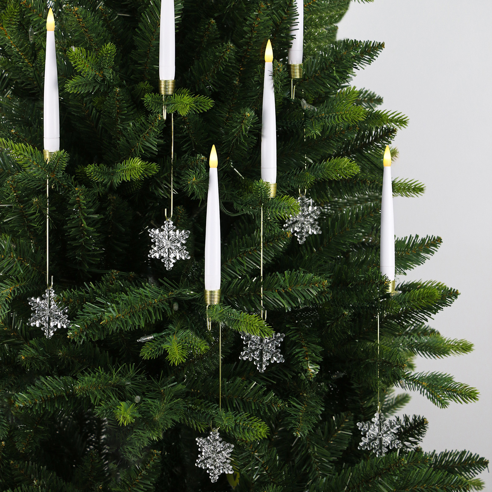 Ein Weihnachtsbaum mit weißen Kerzenlichtern und silbernen Schneeflockenornamenten.