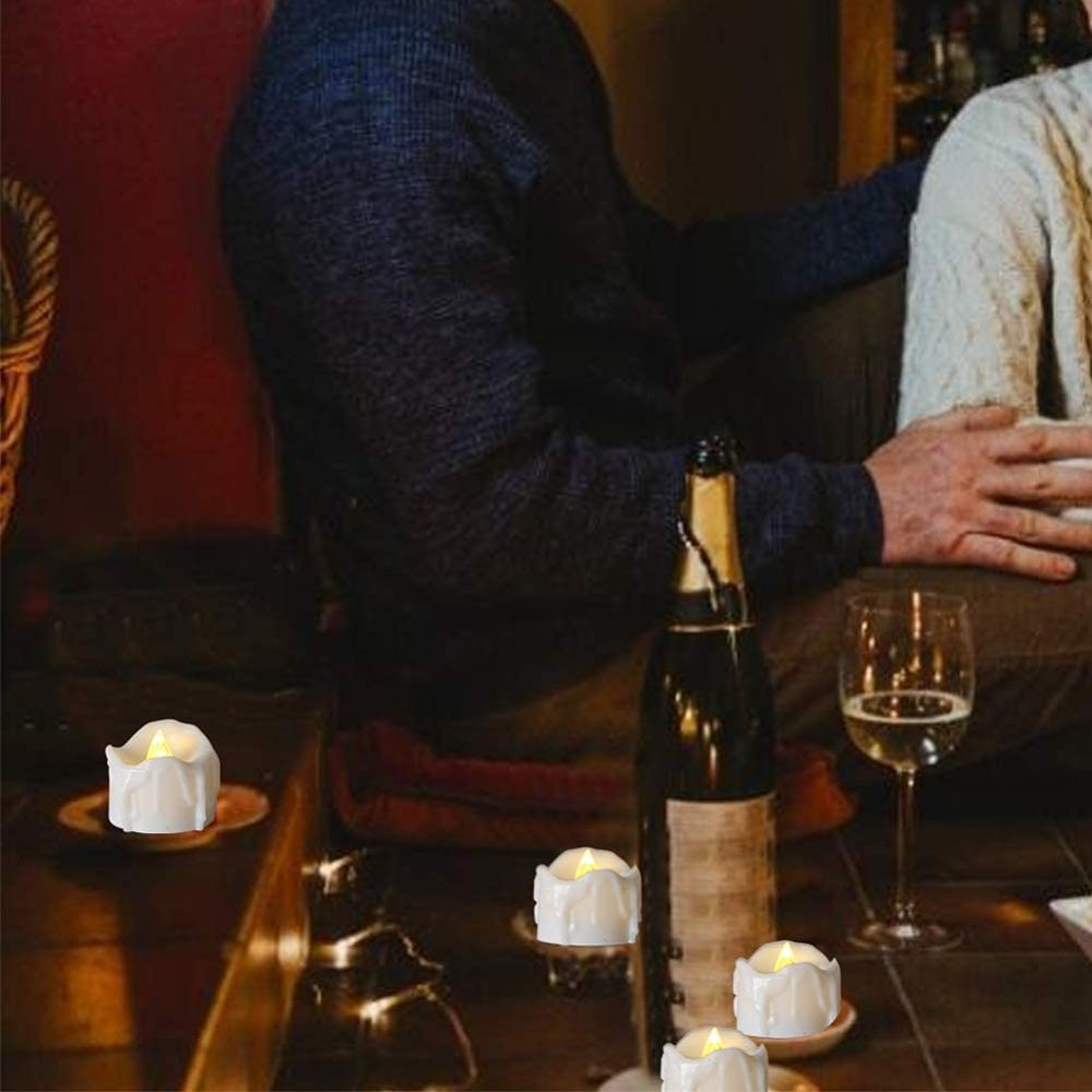 Kerzen auf einem Tisch. Eine Weinflasche und ein Glas. Zwei Personen sitzen. Warme Töne, weiches Licht und eine gemütliche Atmosphäre.