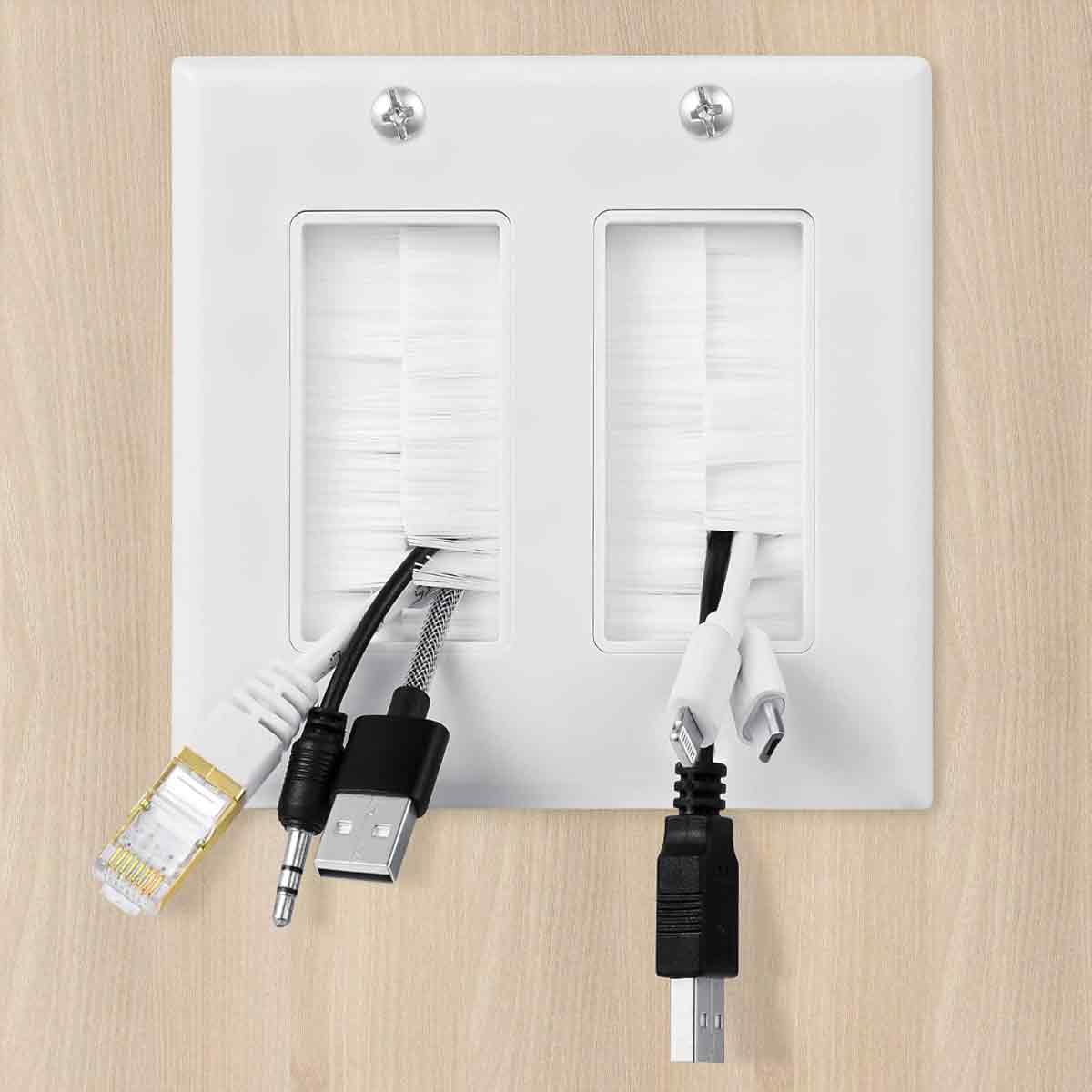 Weiße Wandplatte mit zwei rechteckigen Öffnungen. Kabel verschiedener Typen und Farben sind durch die Öffnungen gesteckt.