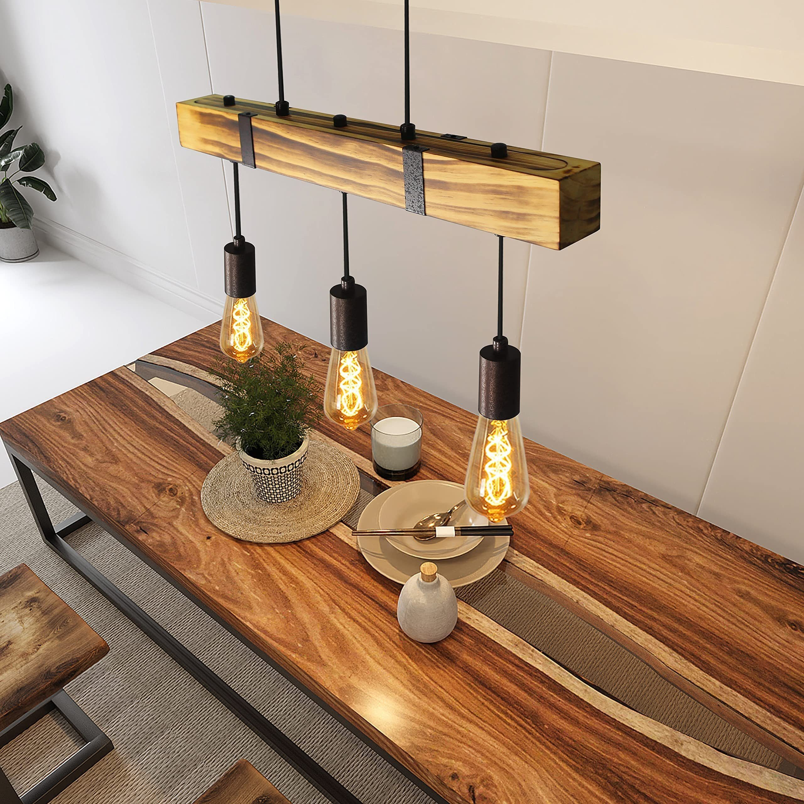 Holztisch mit drei Hängelampen, einer Pflanze und Geschirr. Hintergrund ist eine weiße Wand und Teppich.