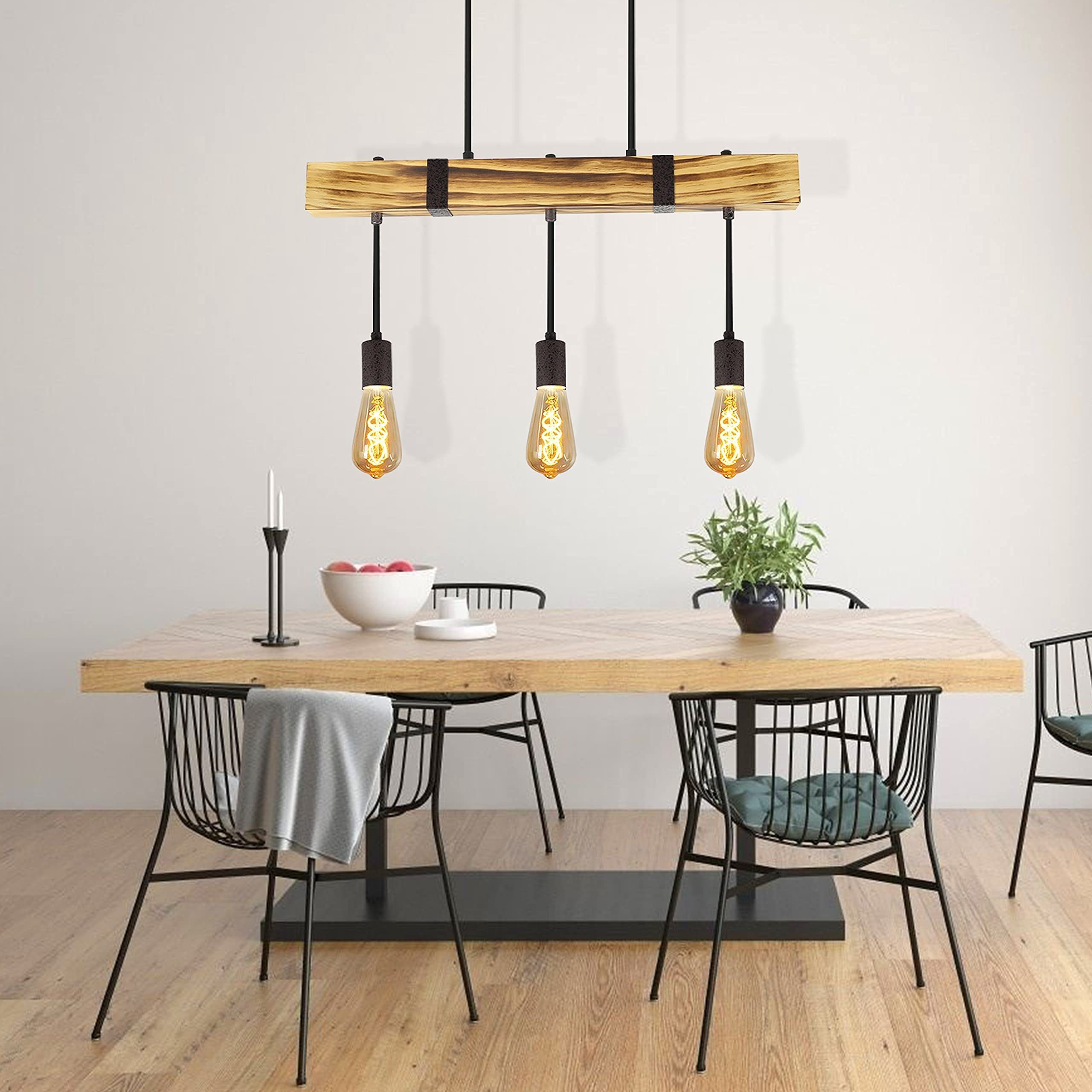 Esszimmer mit Holztisch, schwarzen Stühlen und Leuchte. Es gibt auch eine Pflanze und eine Obstschale.