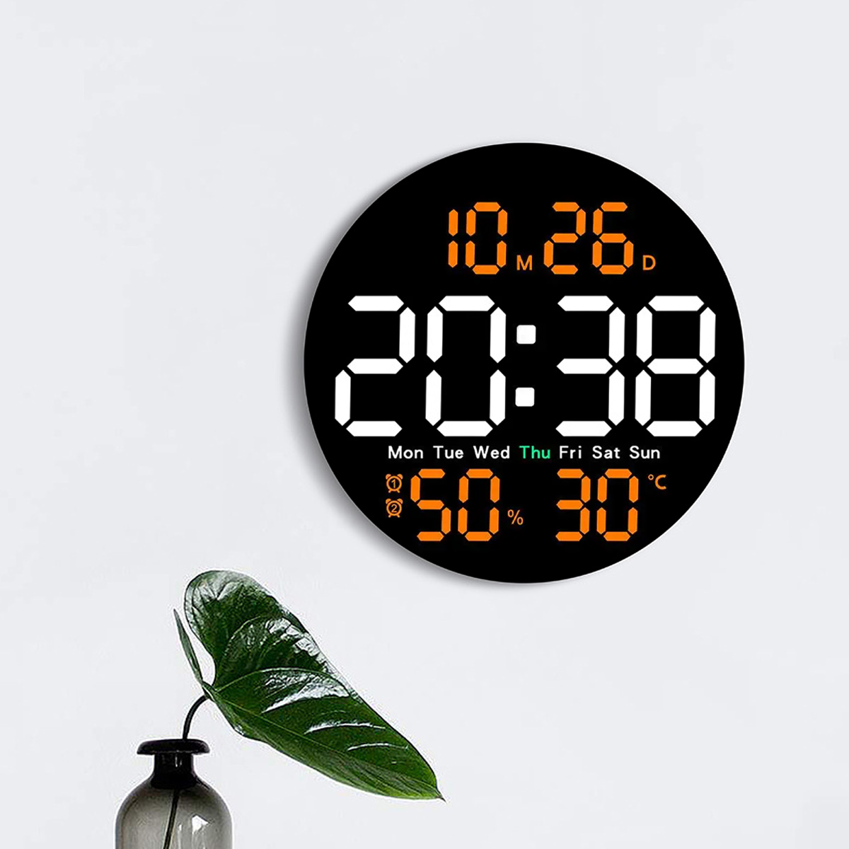 Eine Digitaluhr zeigt 20:38 Uhr, Datum 10.26, 50 % Luftfeuchtigkeit und 30 °C an. Eine Pflanze steht in einer Vase.