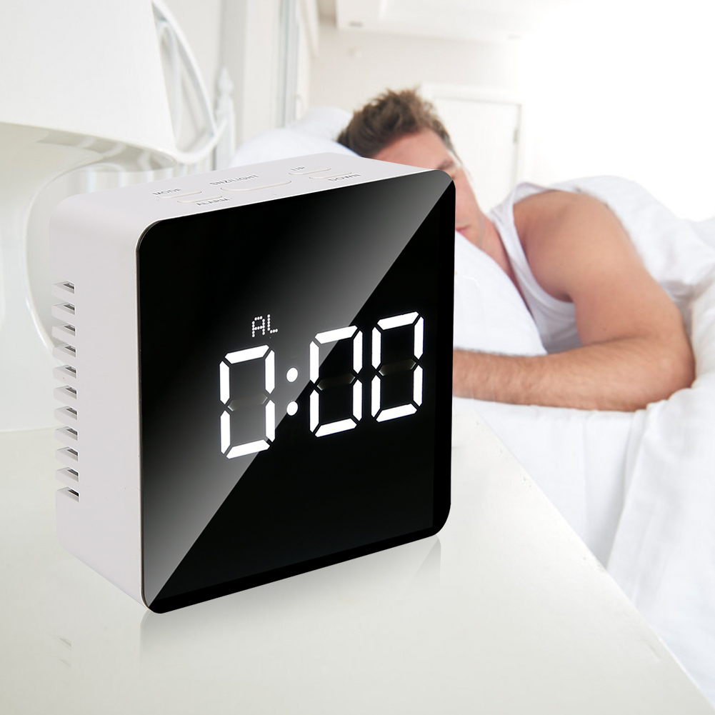 Ein weißer Wecker zeigt '0:00' auf einem schwarzen Bildschirm. Im Hintergrund liegt ein Mann im Bett. Die Szene deutet auf Morgen hin.