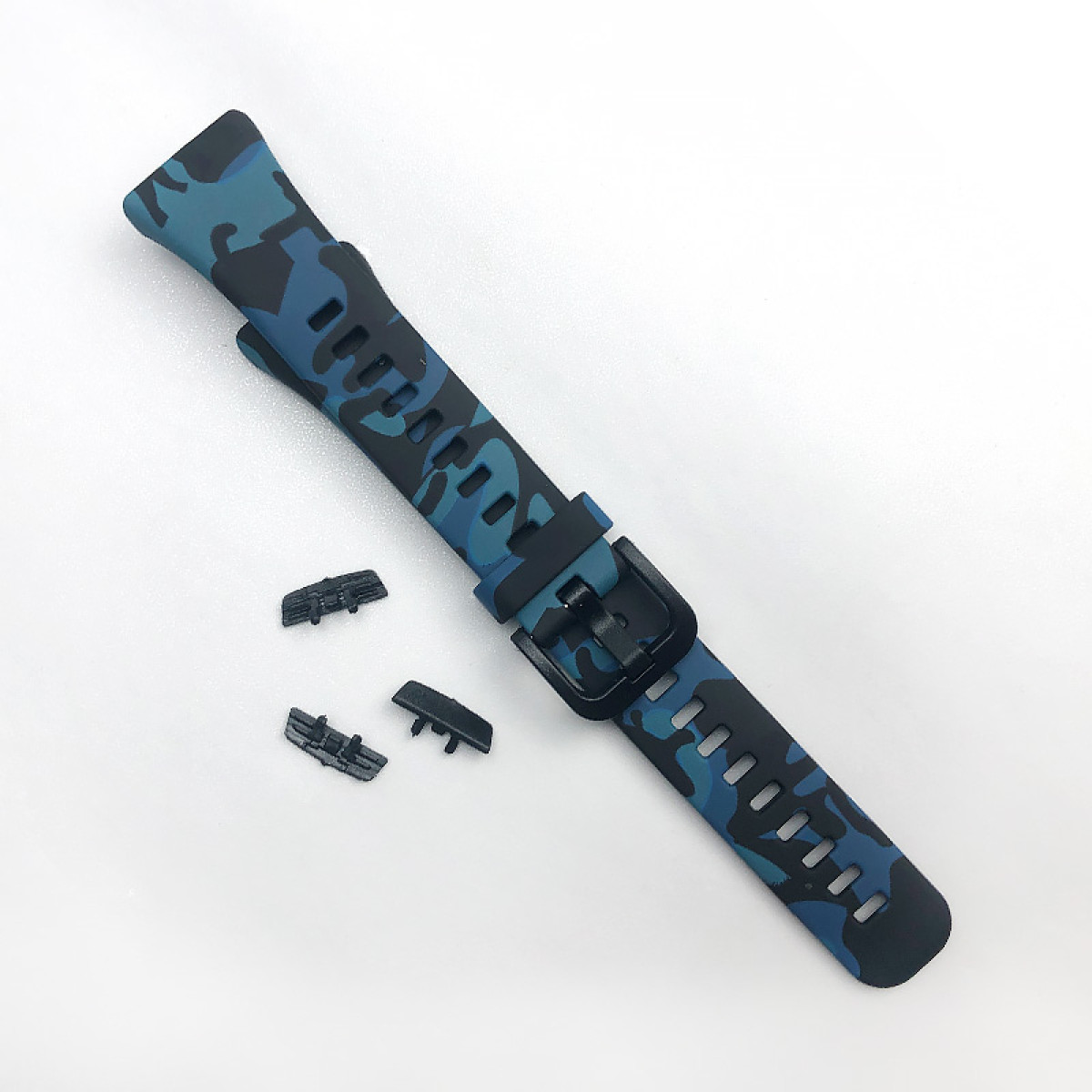 Ein Armband mit blauem Tarnmuster, schwarzer Schnalle und drei kleinen schwarzen Steckern auf weißem Untergrund.