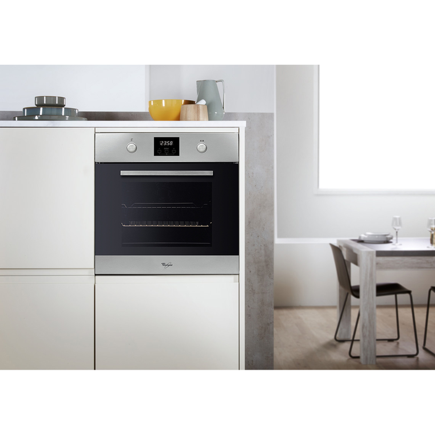Scena cucina con forno, tavolo e sedie. Il forno ha display digitale e porta a vetro. Tavolo apparecchiato con piatti e bicchieri.