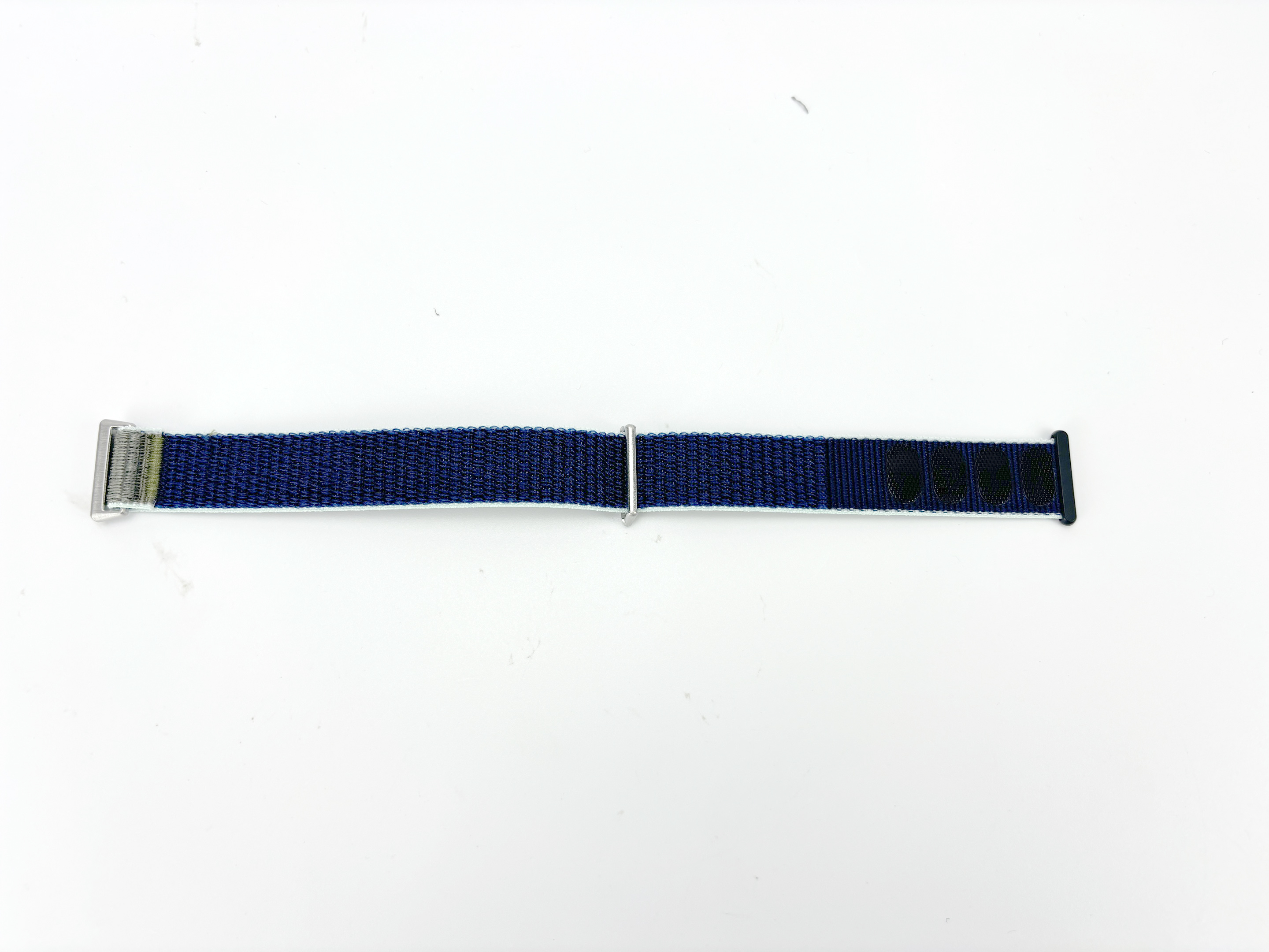 Ein blaues Uhrenarmband mit Metallschnalle und schwarzen Klettverschlüssen auf weißem Untergrund.