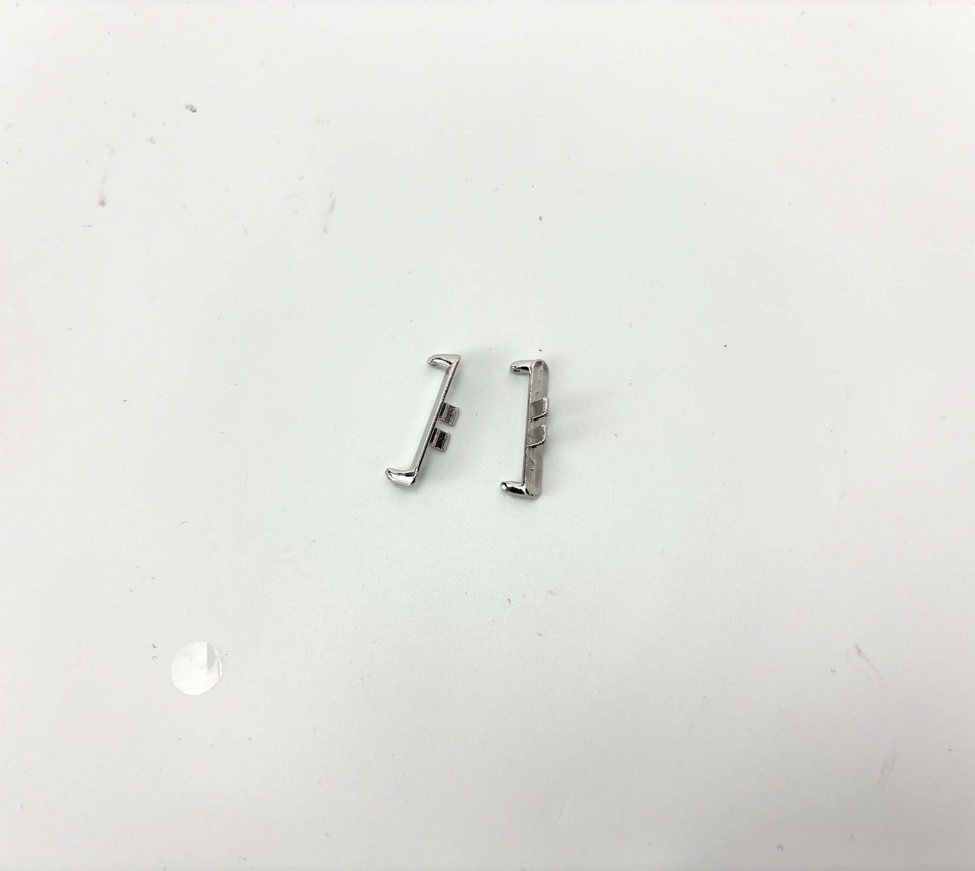 Due clip in metallo argentato su una superficie bianca. Una clip è piegata, entrambe hanno una piccola parte rettangolare.