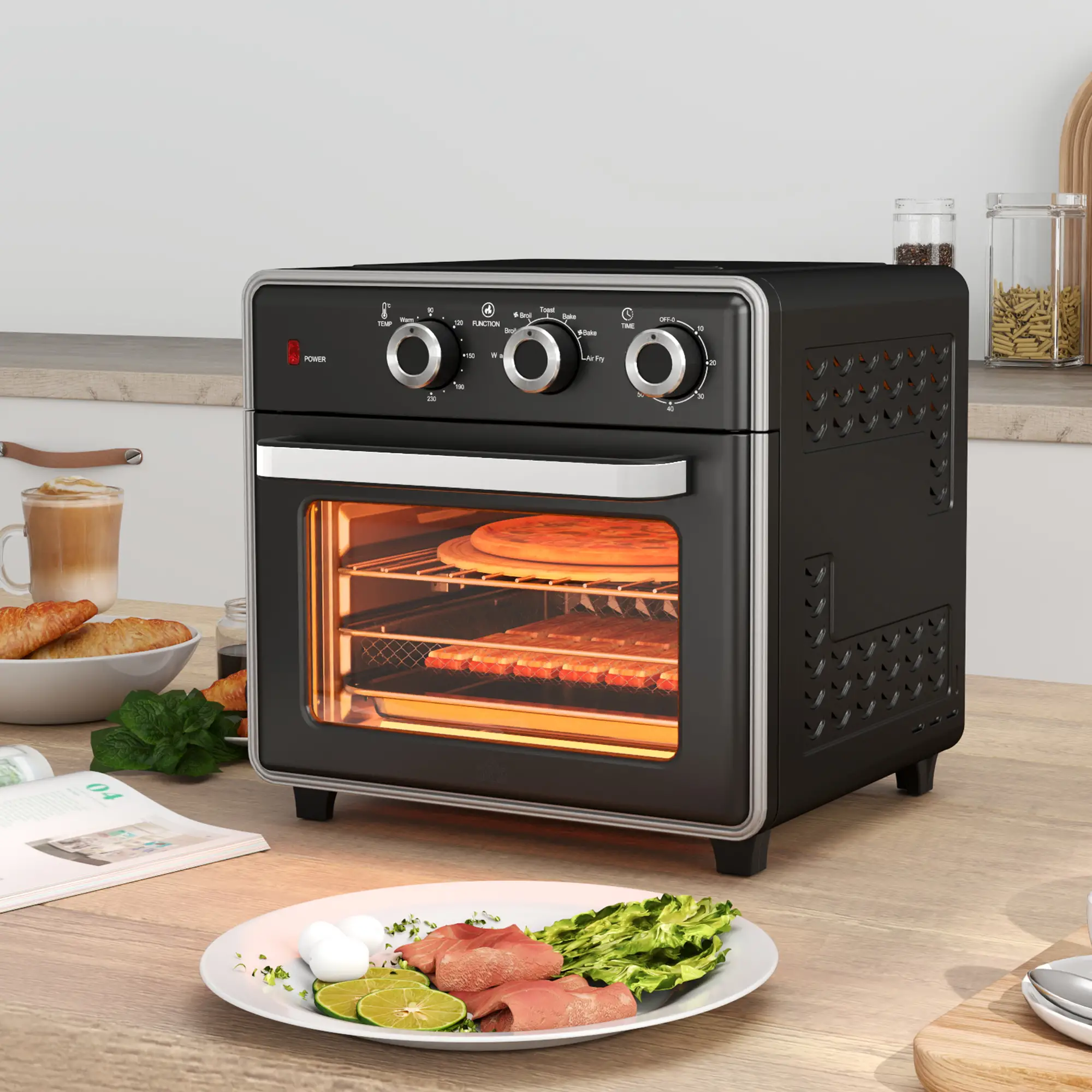 Ein schwarzer Luftfritteuse mit Pizza. Auf dem Tisch befinden sich Lebensmittel wie Fleisch, Limetten, Salat, Croissants und Kaffee.