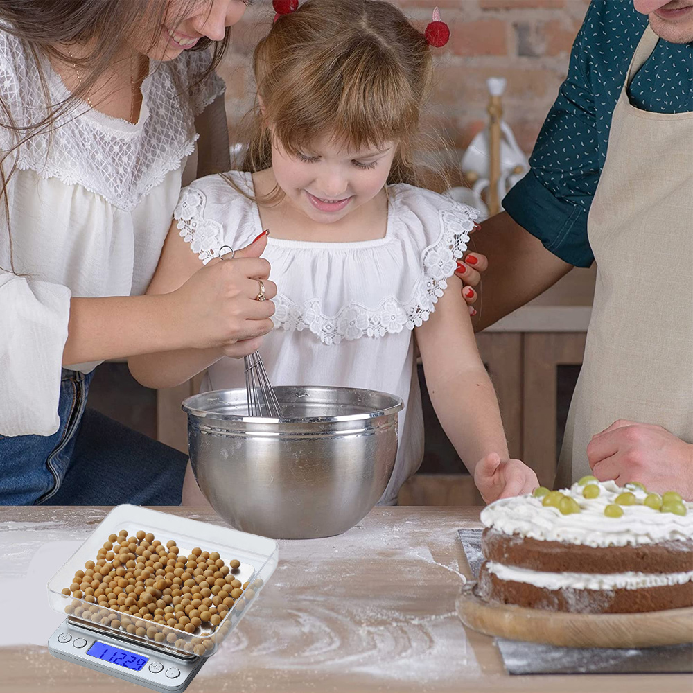 Eine Familie backt zusammen. Ein Kind schlägt Teig in einer Metallschüssel. Ein Kuchen mit Trauben und eine Waage mit Samen stehen auf dem Tisch.
