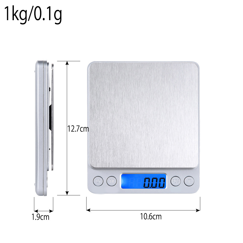 Eine Digitalwaage zeigt 0,00 an. Die Abmessungen sind 12,7 cm x 10,6 cm x 1,9 cm. Der Text lautet 1 kg/0,1 g.