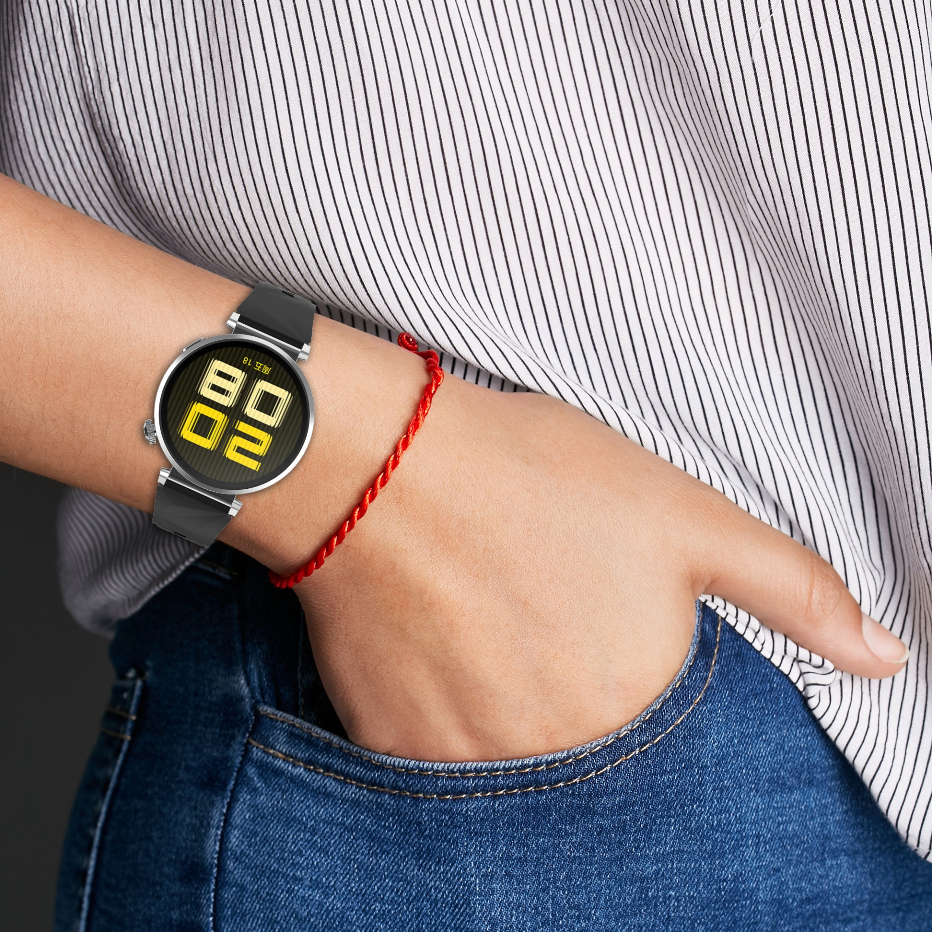 Una persona con smartwatch e braccialetto rosso. Indossa una camicia a righe e jeans.