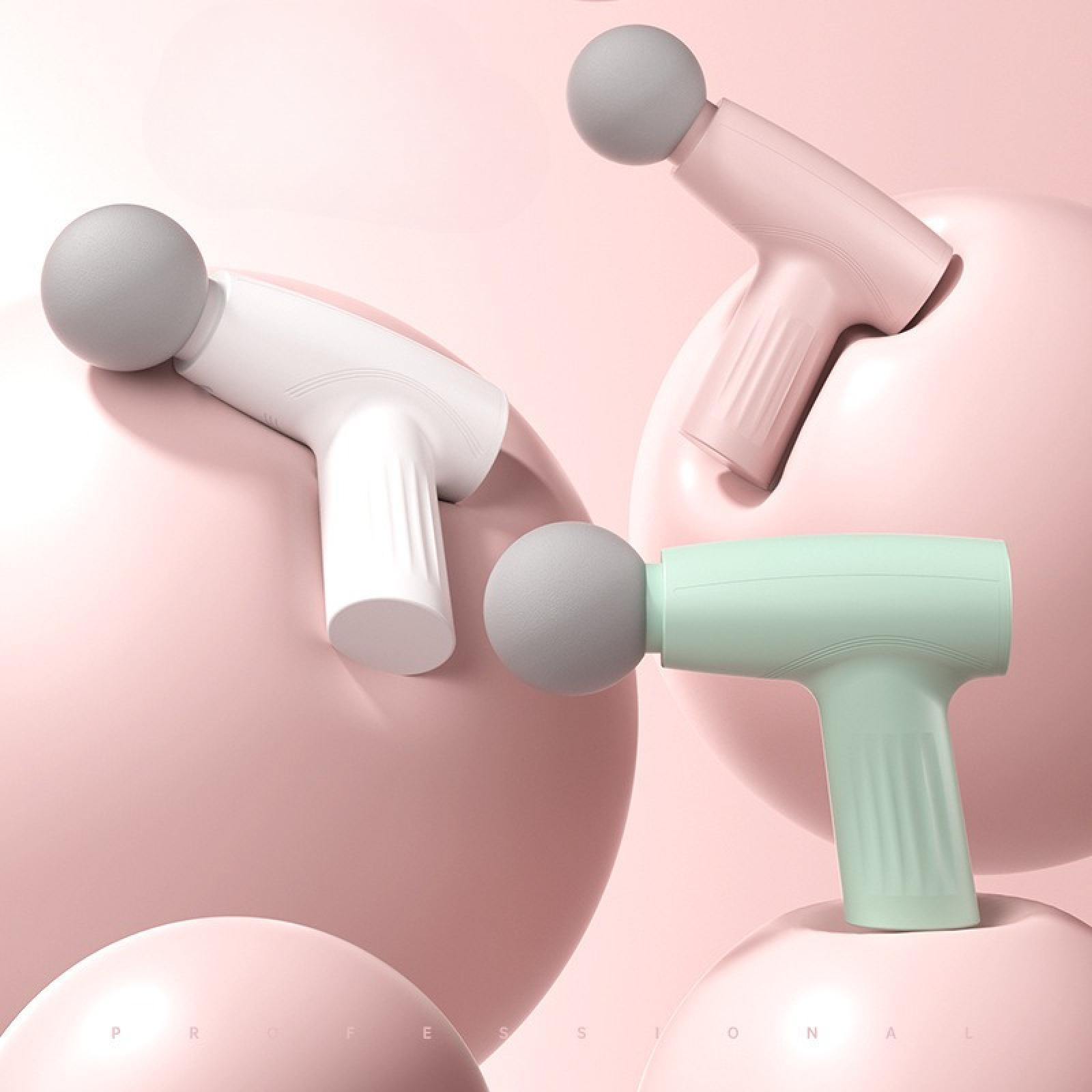 Drei Massagepistolen in verschiedenen Farben (weiß, rosa und grün) liegen auf rosa, kugelförmigen Formen.