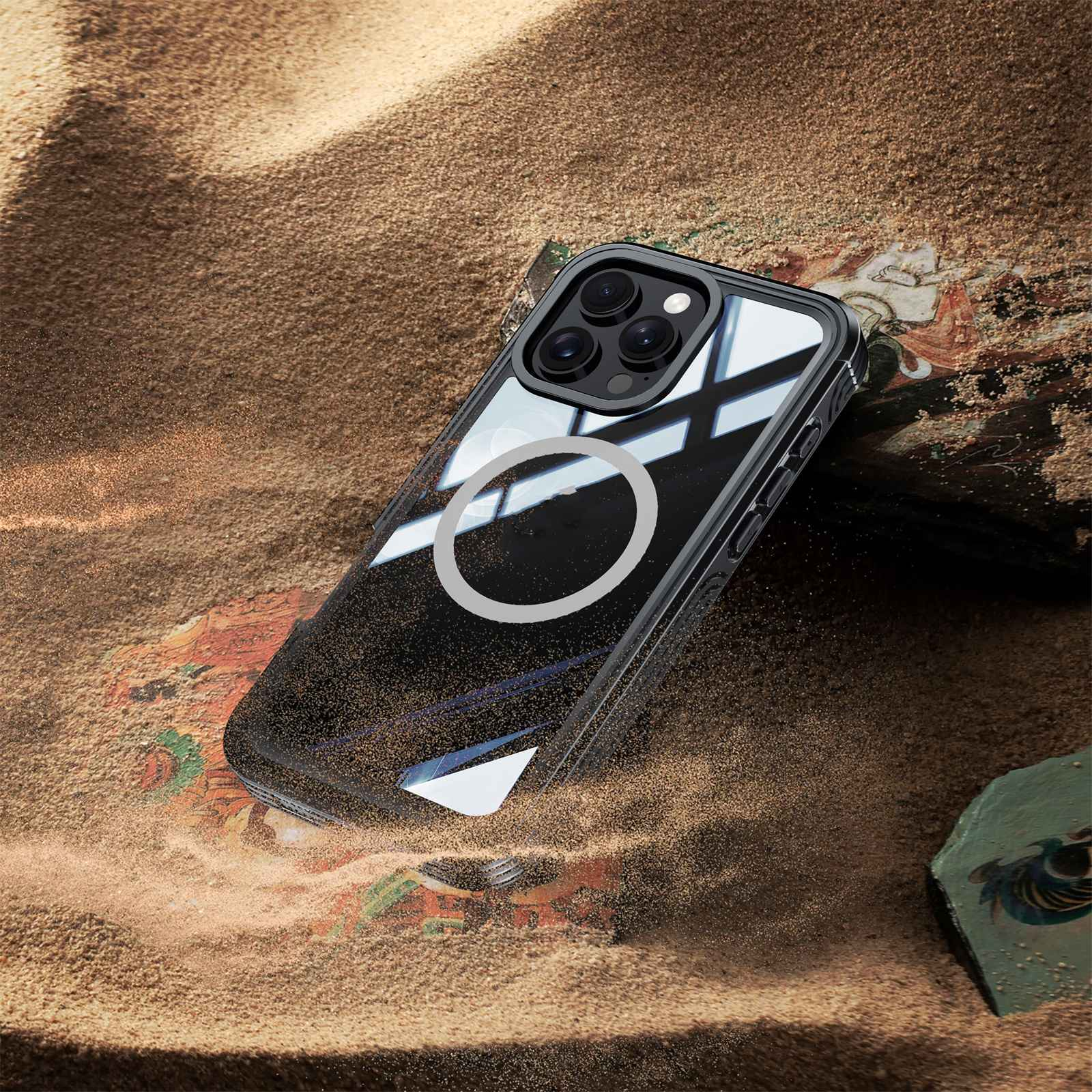 Ein Telefon mit Hülle liegt auf Sand. Der Hintergrund hat eine bunte Oberfläche und Felsen.