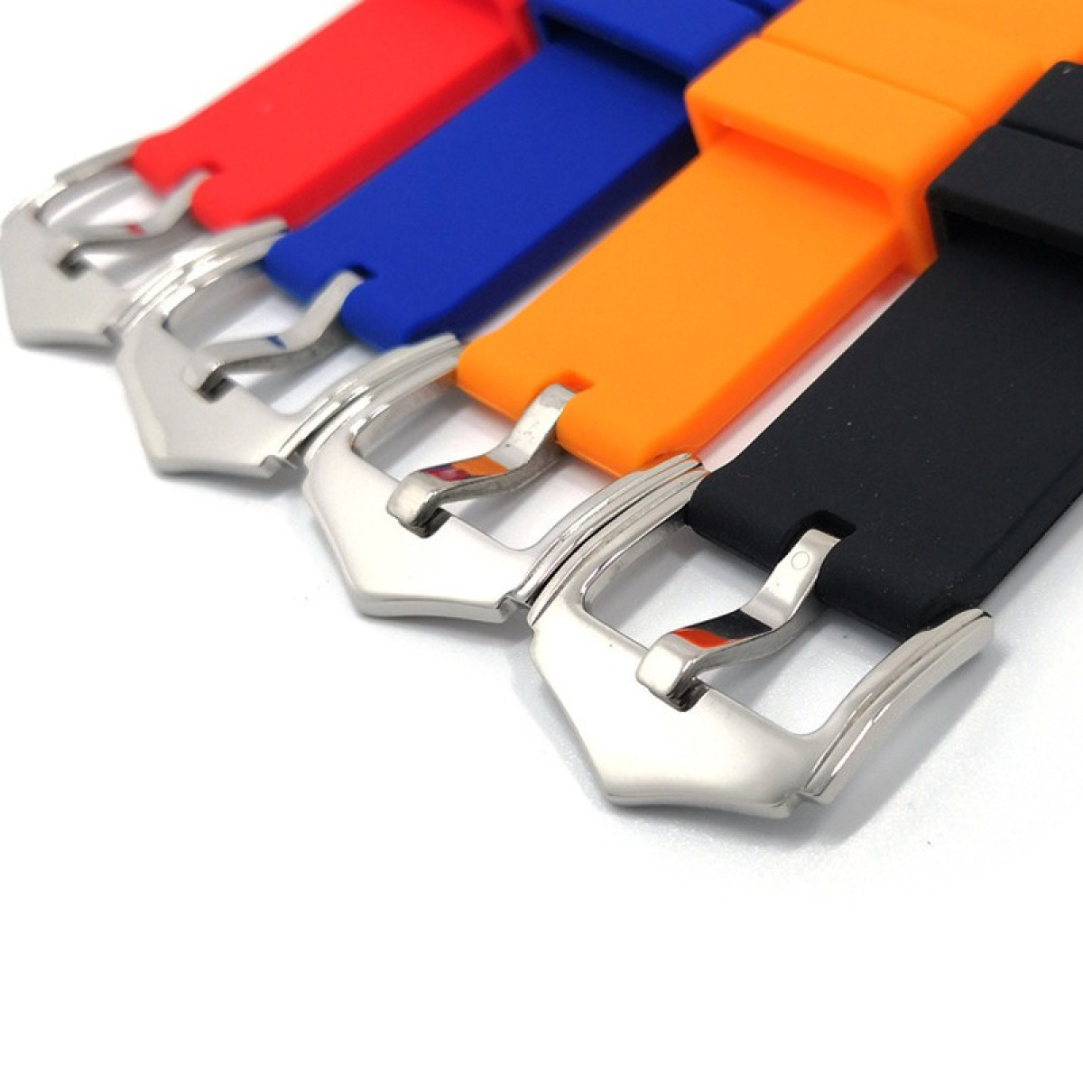 Quattro cinturini colorati con fibbie argentate sono esposti su sfondo bianco. I colori sono rosso, blu, arancione e nero.