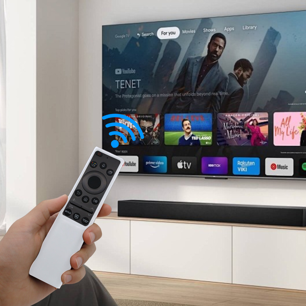 Eine Hand hält eine weiße Fernbedienung. Ein Fernseher zeigt einen Film und Apps. WLAN-Symbol über dem Fernseher. Darunter eine schwarze Soundbar auf einem weißen Schrank.