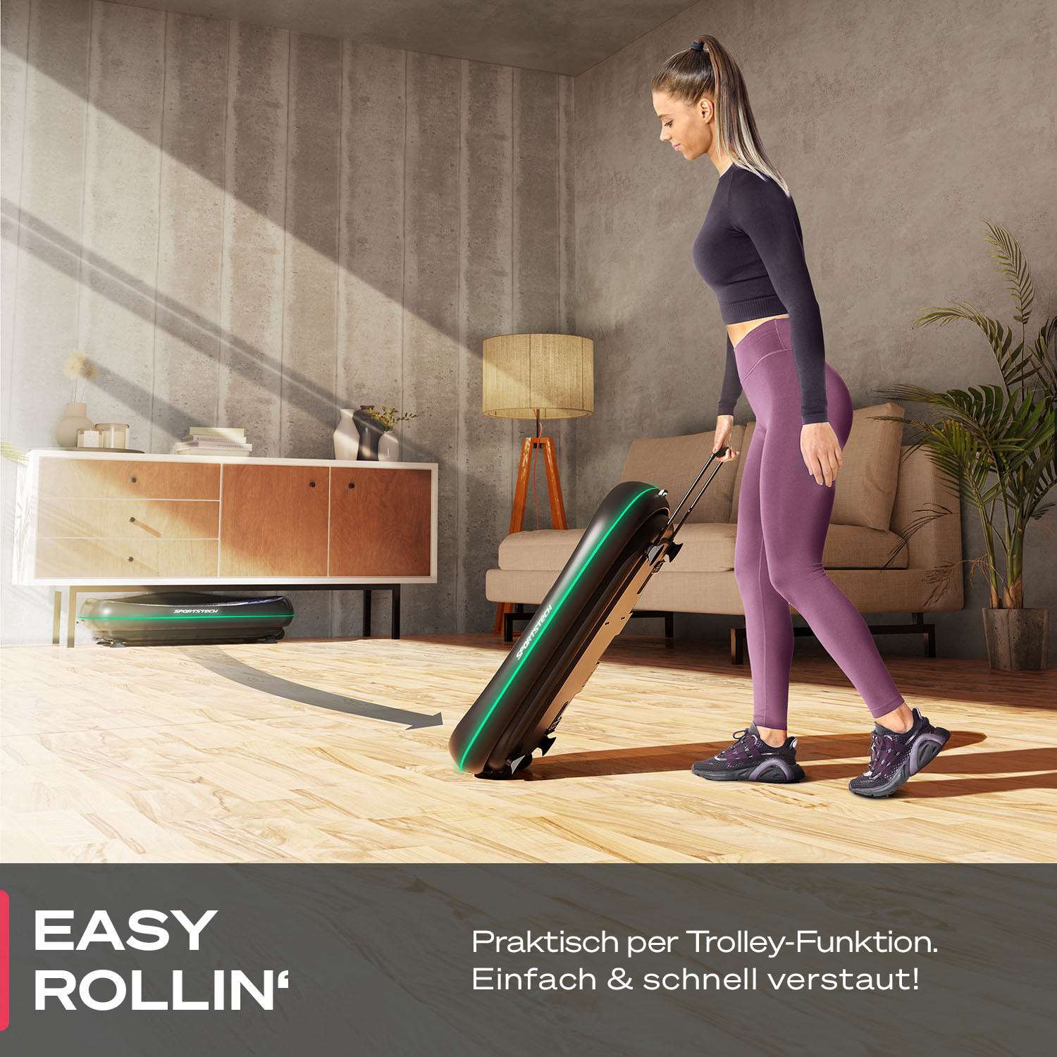 Eine Frau in lila Leggings rollt ein schwarzes Trainingsgerät. Es gibt einen Schrank, ein Sofa und eine kleine grüne Maschine auf dem Boden.