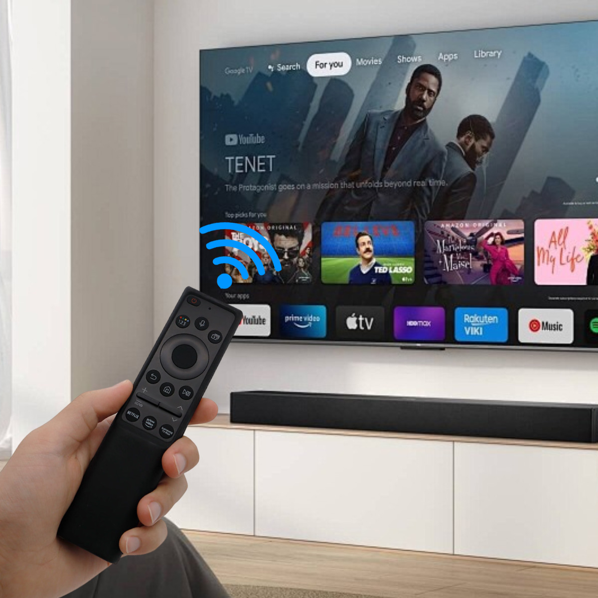 Hand hält eine schwarze Fernbedienung. Ein Fernsehbildschirm zeigt Streaming-Apps und einen Film. Unter dem Fernseher befindet sich eine Soundbar.